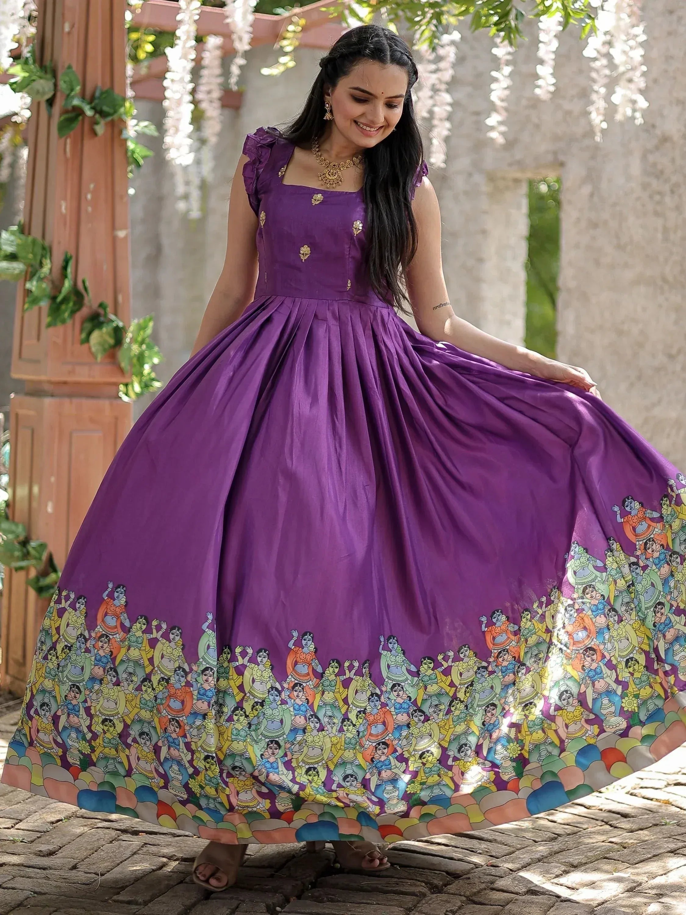 Purple ethnic gown with colorful folk art border, perfect for Indian celebrations and festive occasions.