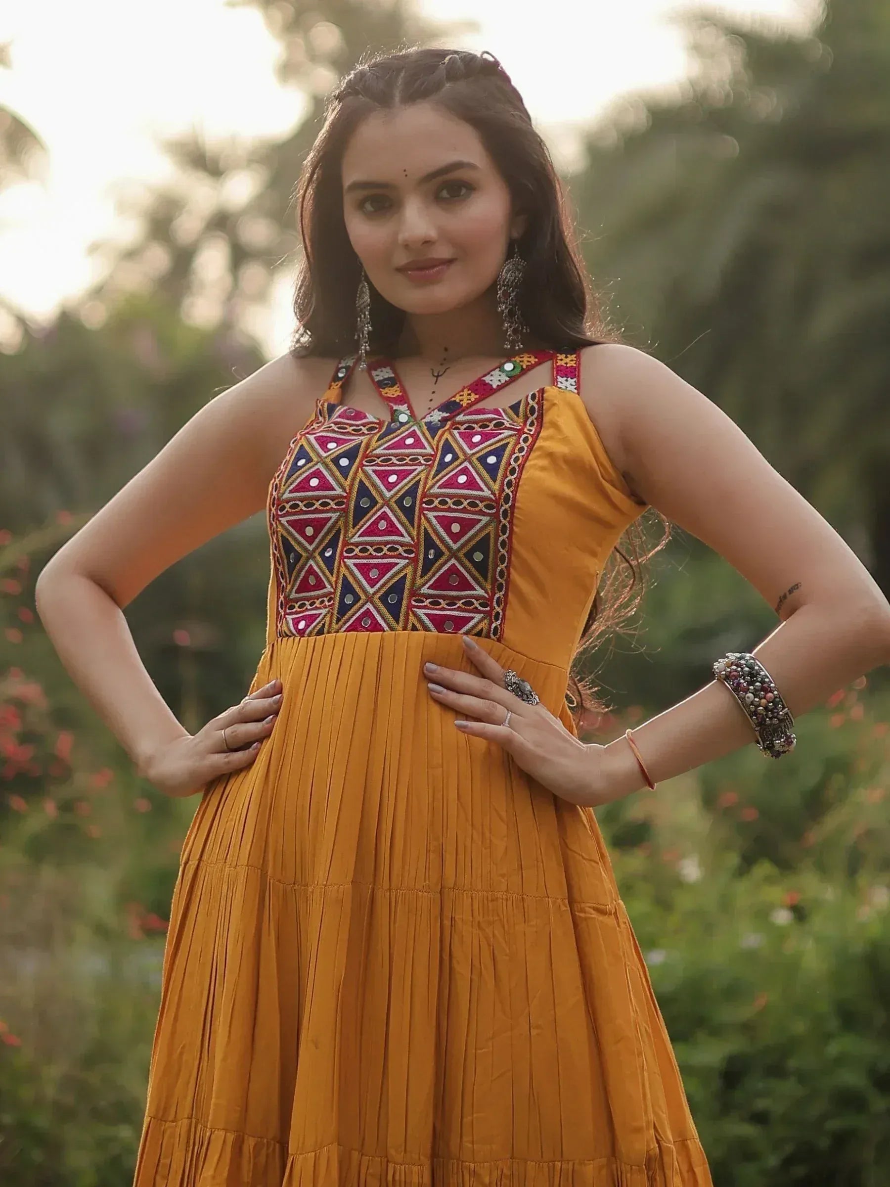 Yellow ethnic gown with colorful mirror work and pleated skirt, perfect for Indian festive occasions