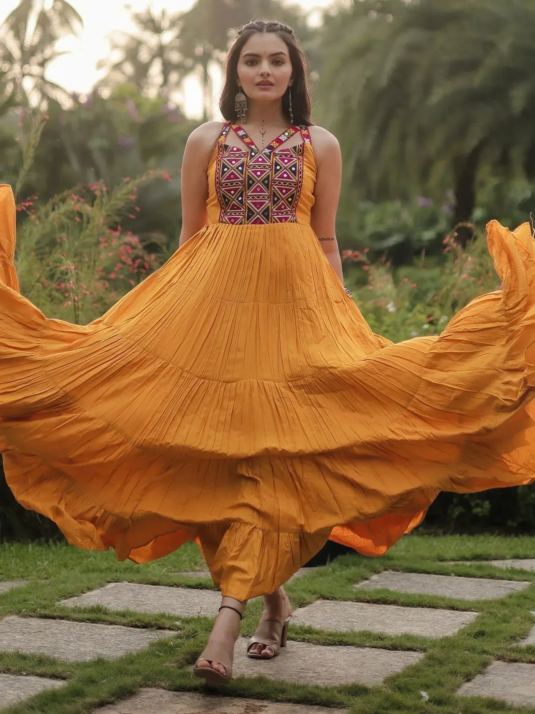 Woman twirling in mustard yellow ethnic gown with embroidered bodice, perfect for Indian festive occasions.