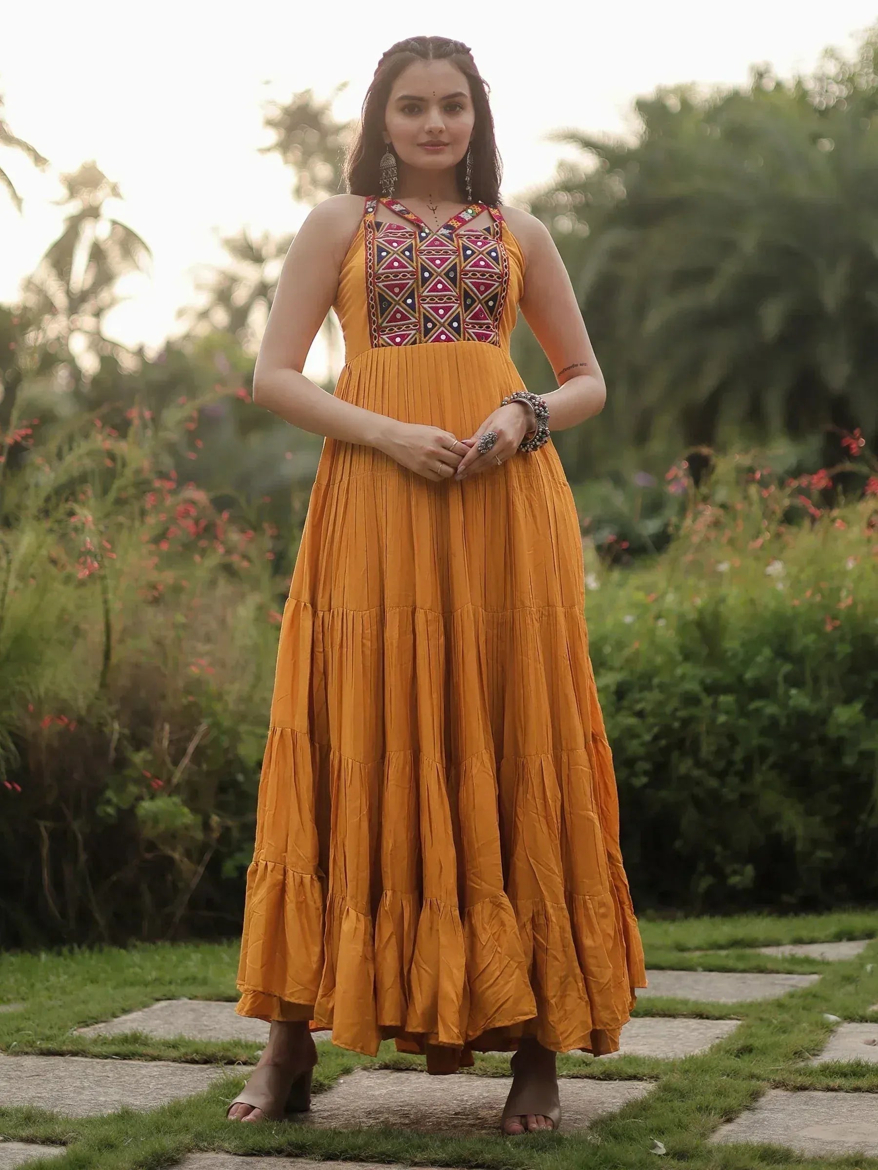 Mustard yellow ethnic gown with colorful geometric embroidery, pleated tiered skirt, perfect for Indian occasions