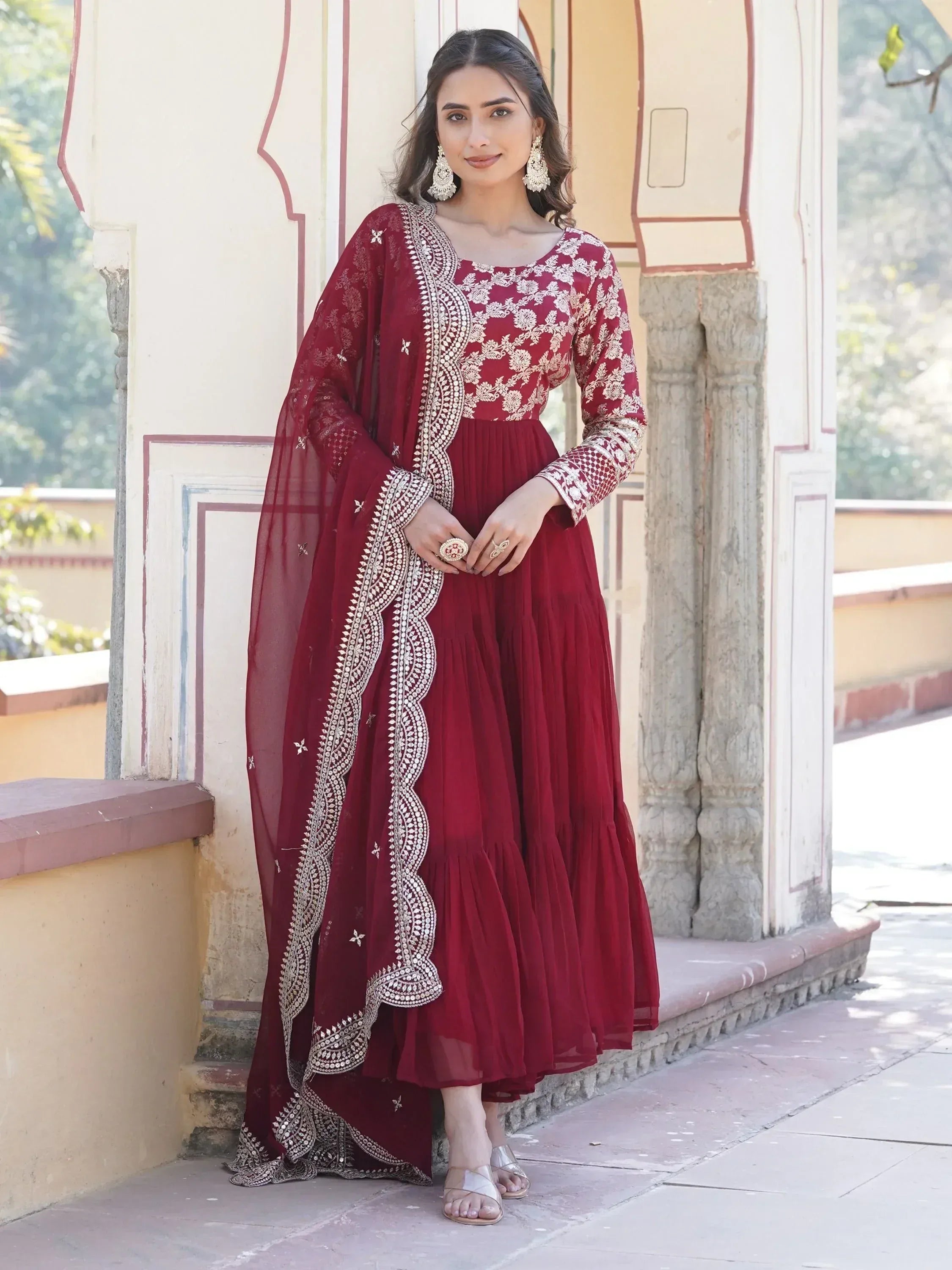 Woman wearing maroon embroidered Indian Anarkali suit with dupatta outdoors