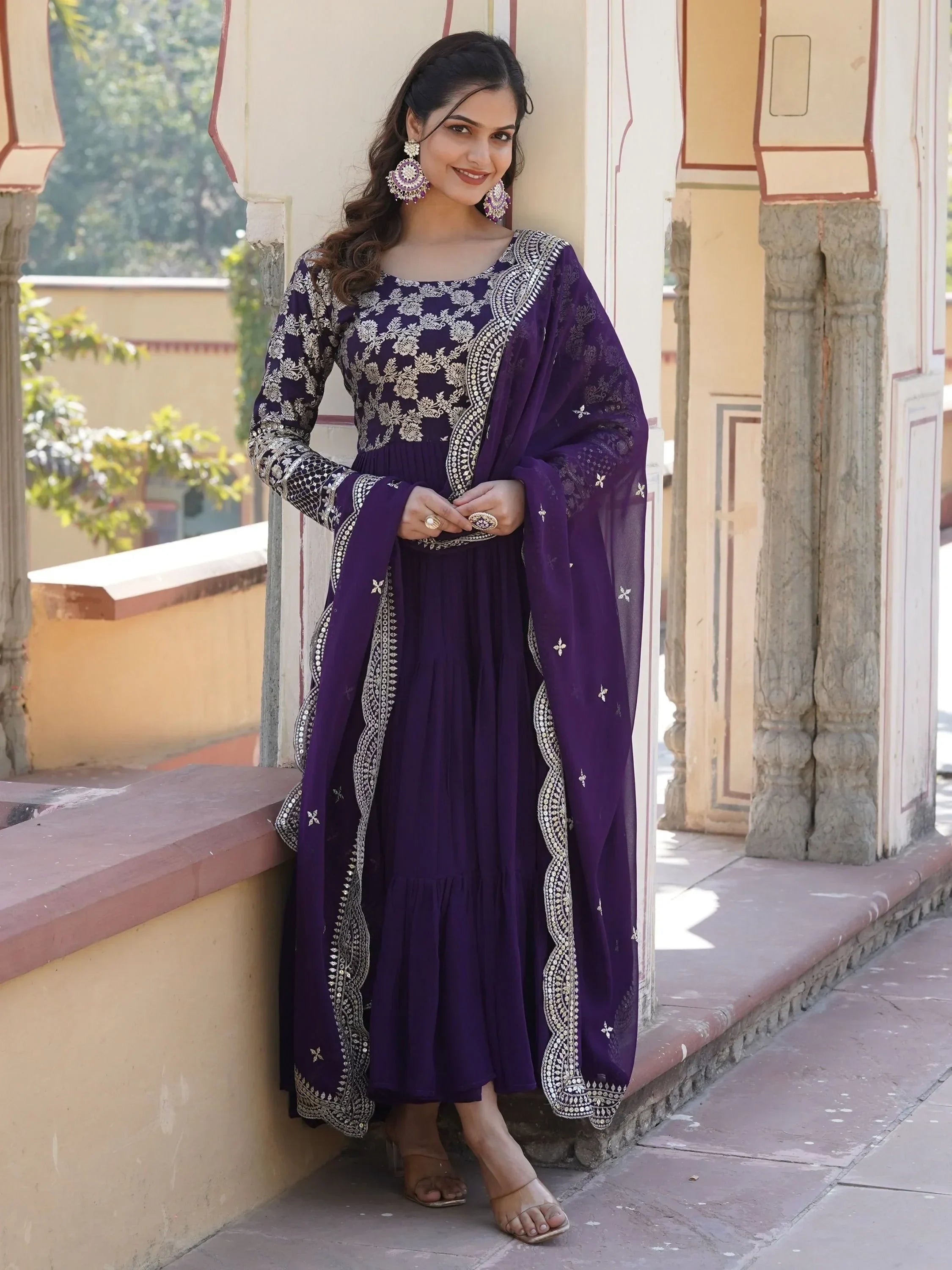 Woman wearing a purple embroidered Anarkali suit with dupatta and statement earrings