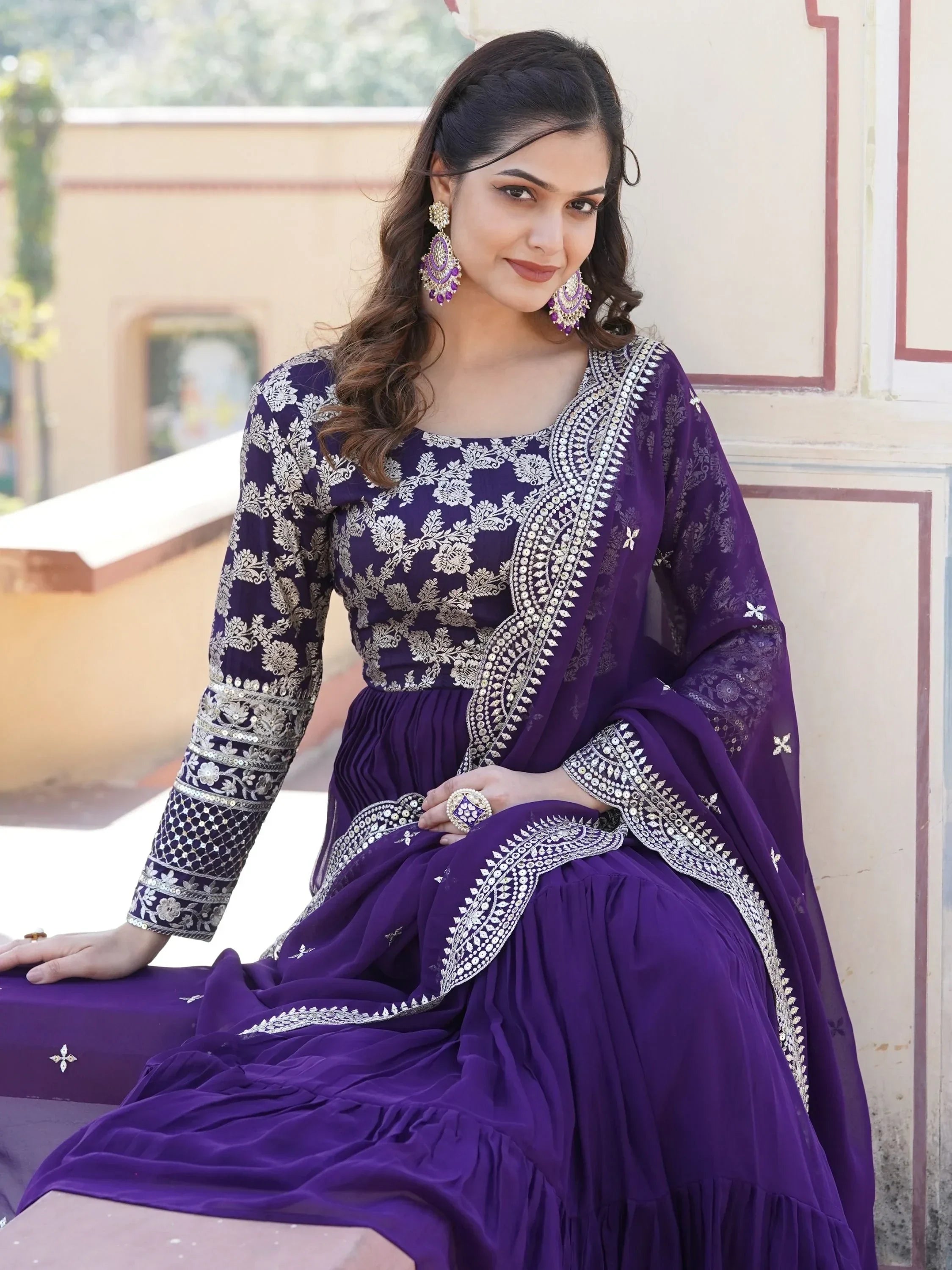 Woman in purple embroidered lehenga choli with matching dupatta and statement earrings