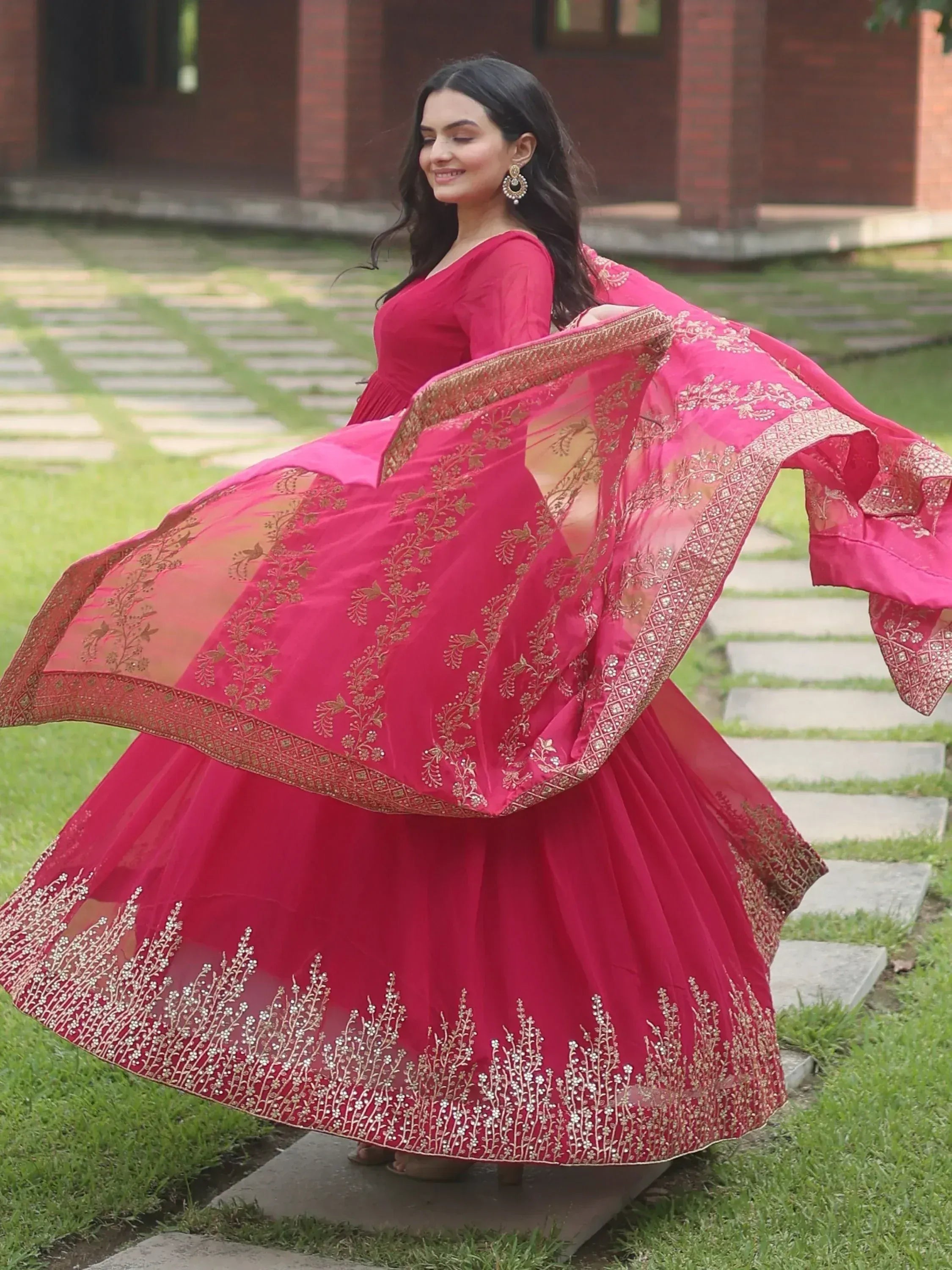 Woman in vibrant pink embroidered lehenga choli with flowing dupatta, perfect for Indian ethnic occasions