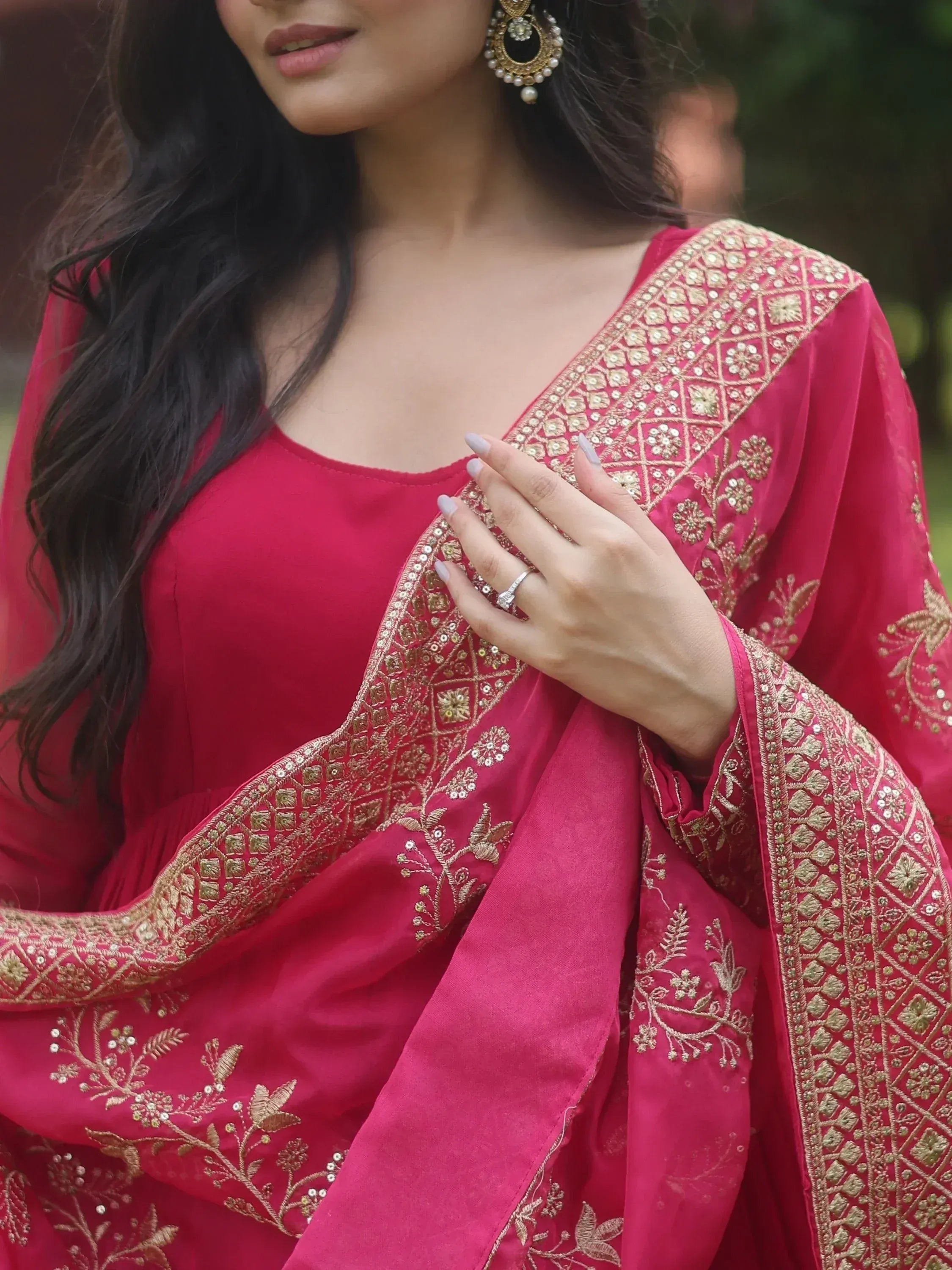 Woman in pink ethnic gown with gold embroidery and pearl earrings, perfect for Indian weddings or festivals.