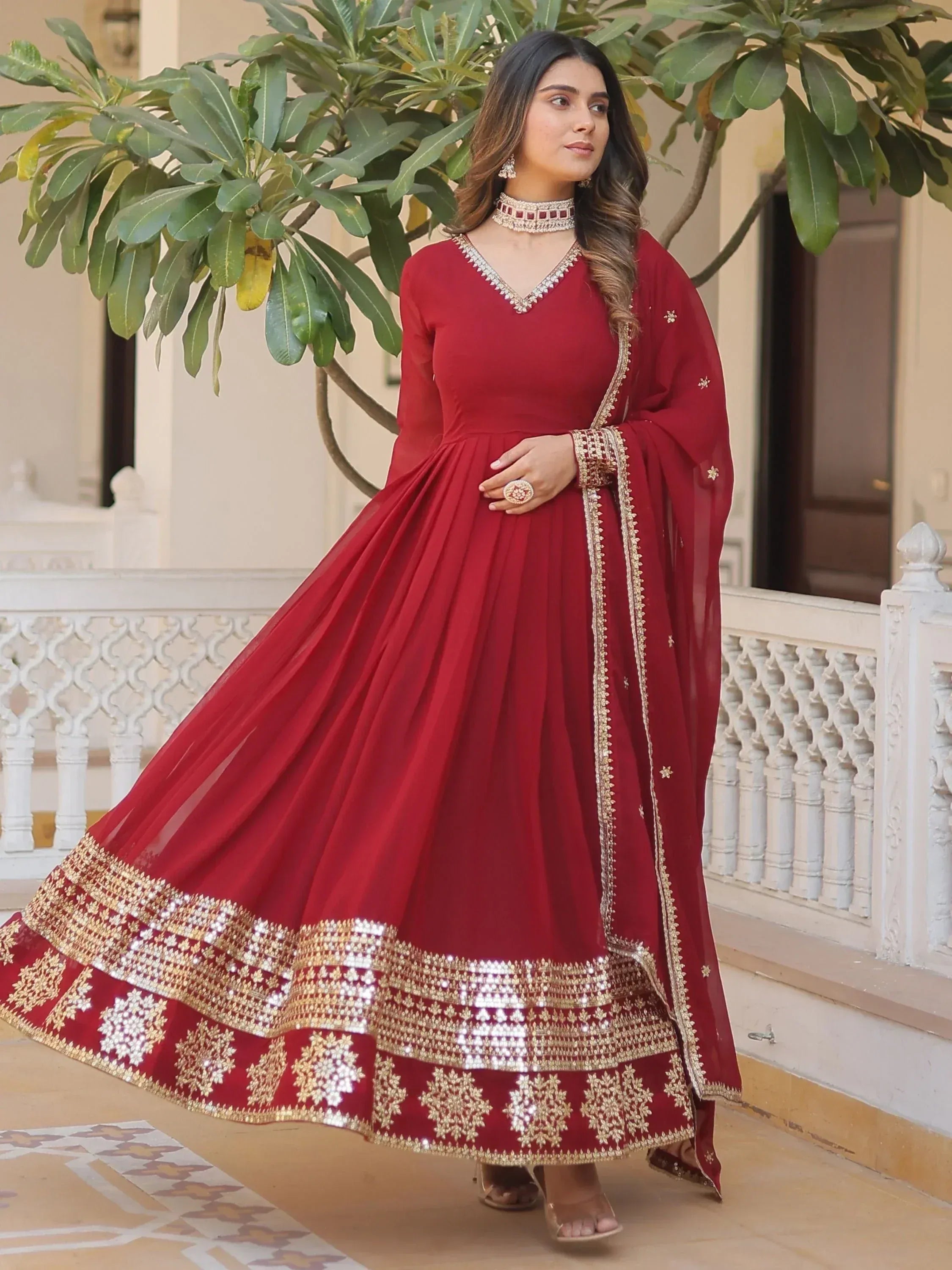Red ethnic anarkali gown with gold embroidery and sequin border, perfect for Indian weddings and festive occasions.