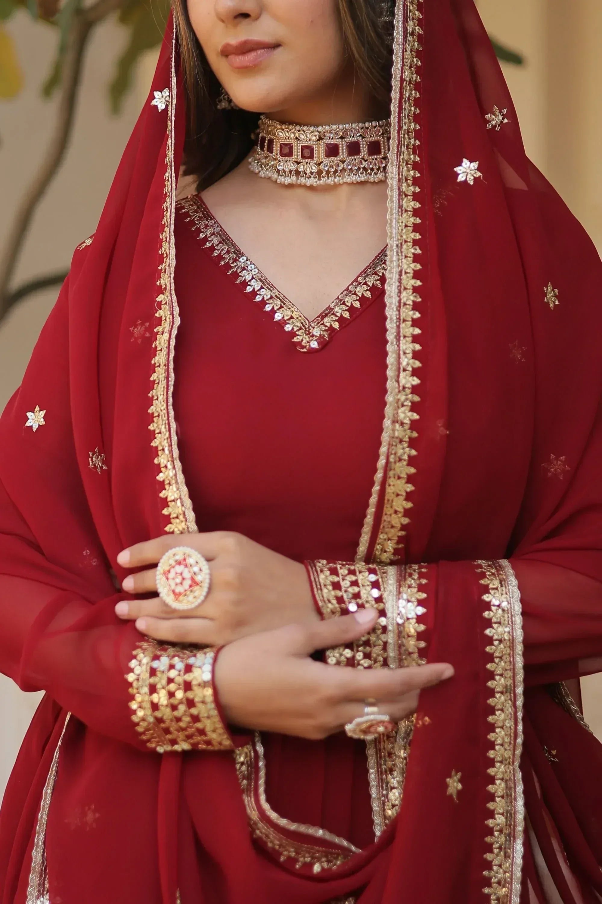 Red ethnic salwar kameez with gold embroidery, matching dupatta, and traditional jewelry for festive occasions