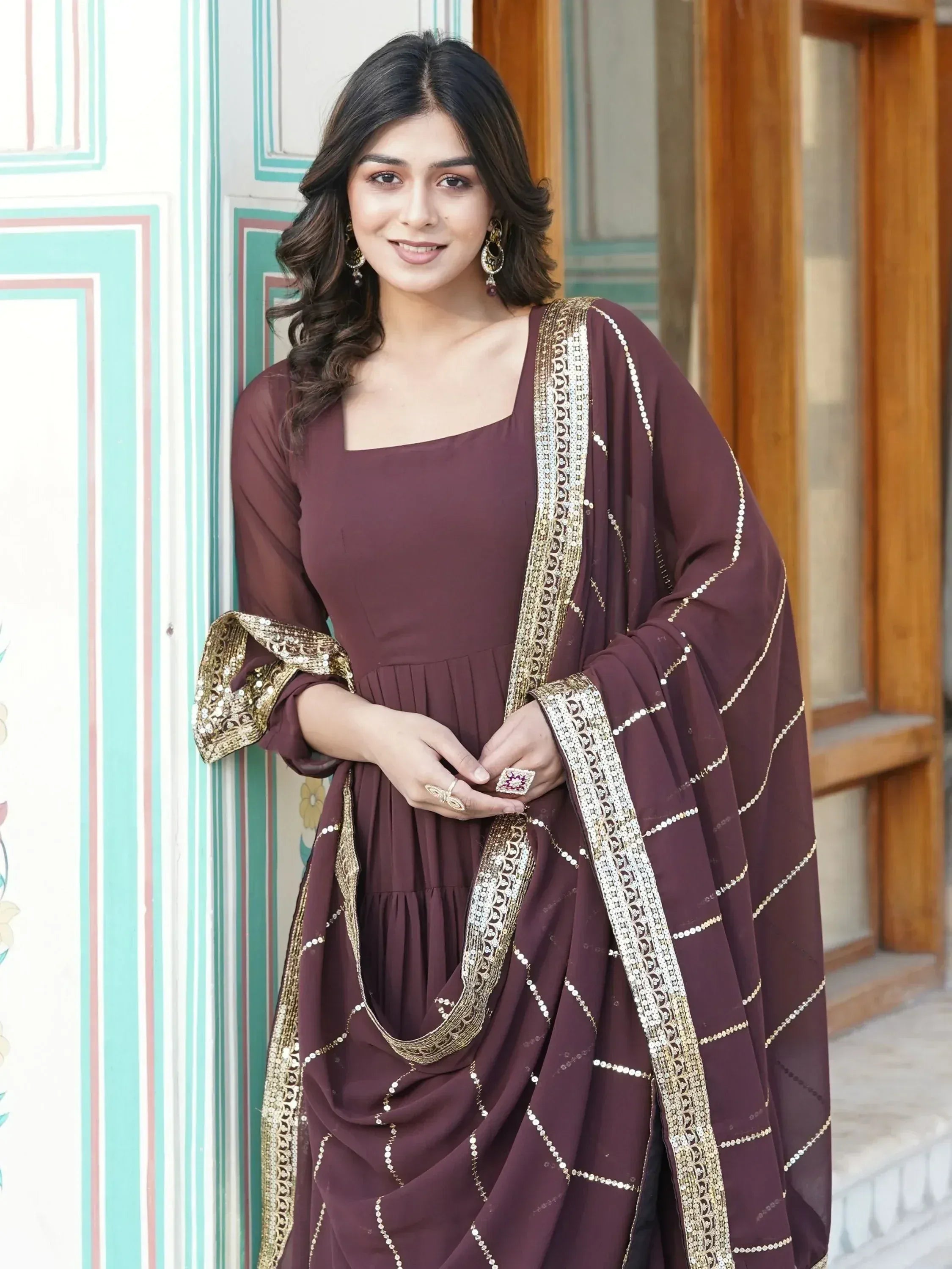 Woman wearing brown ethnic gown with gold embellishments and dupatta