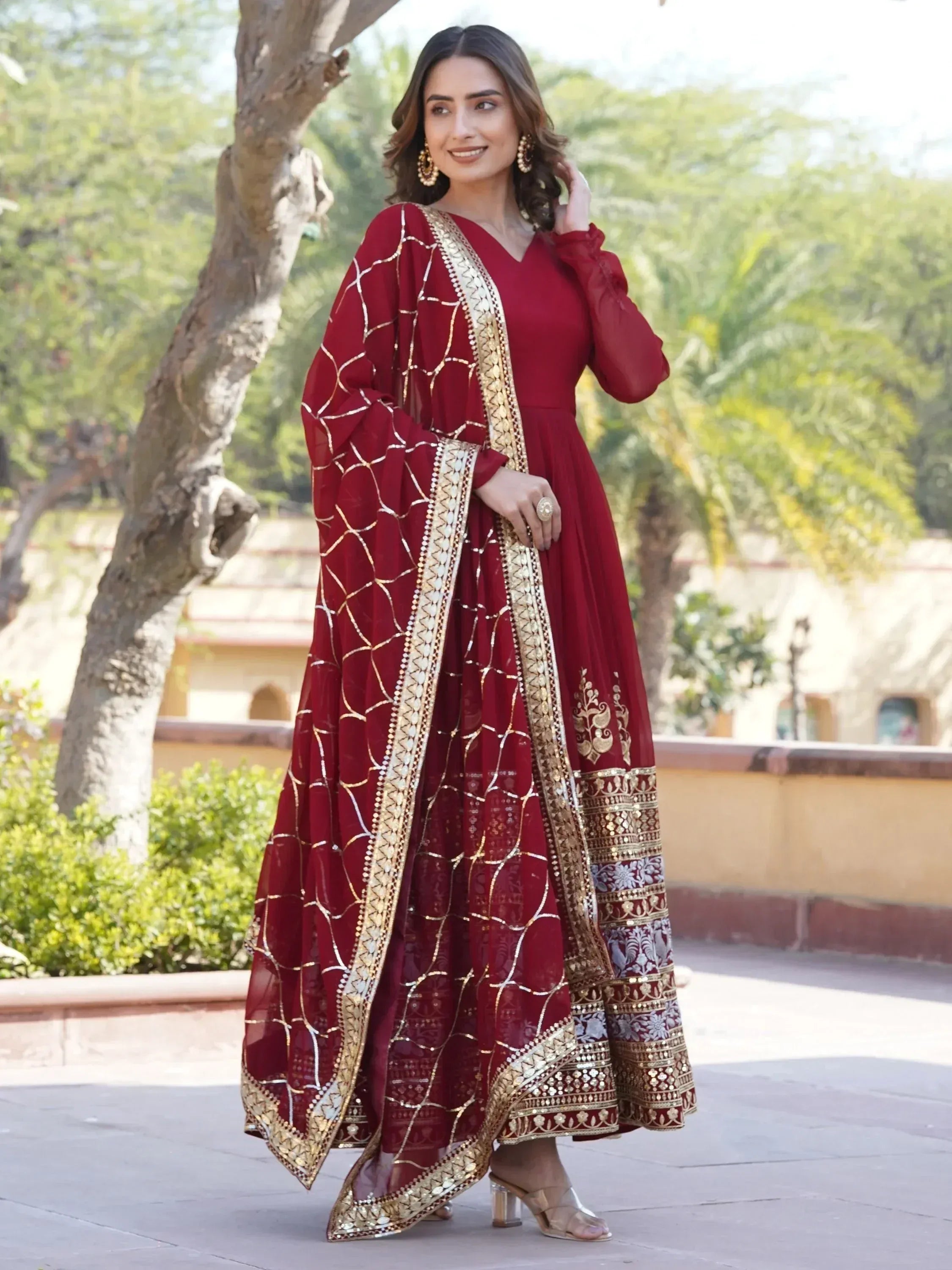 Maroon ethnic gown with gold embroidery and mirror work, perfect for Indian festive occasions