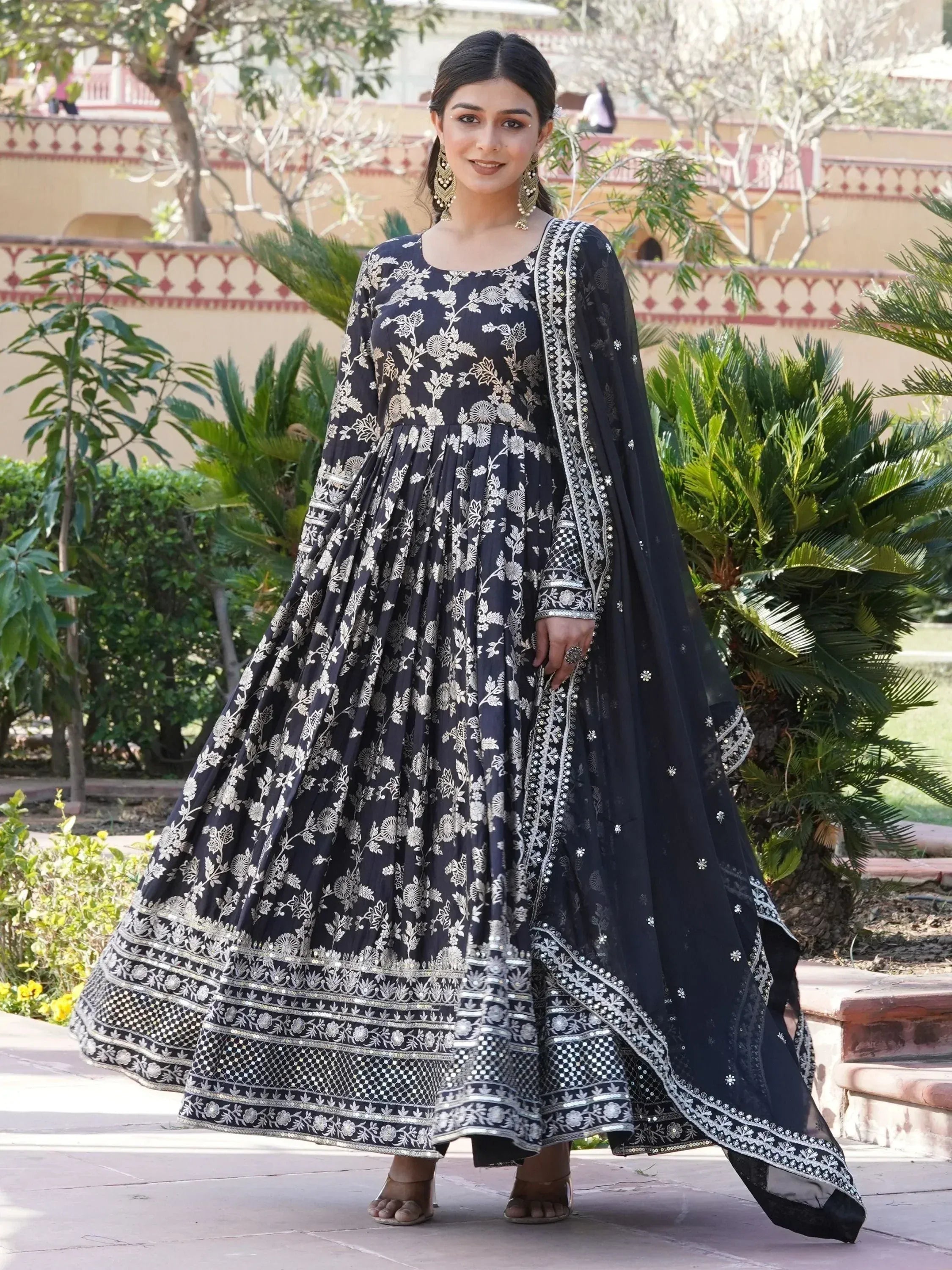 Woman wearing black floral embroidered Anarkali suit with dupatta outdoors