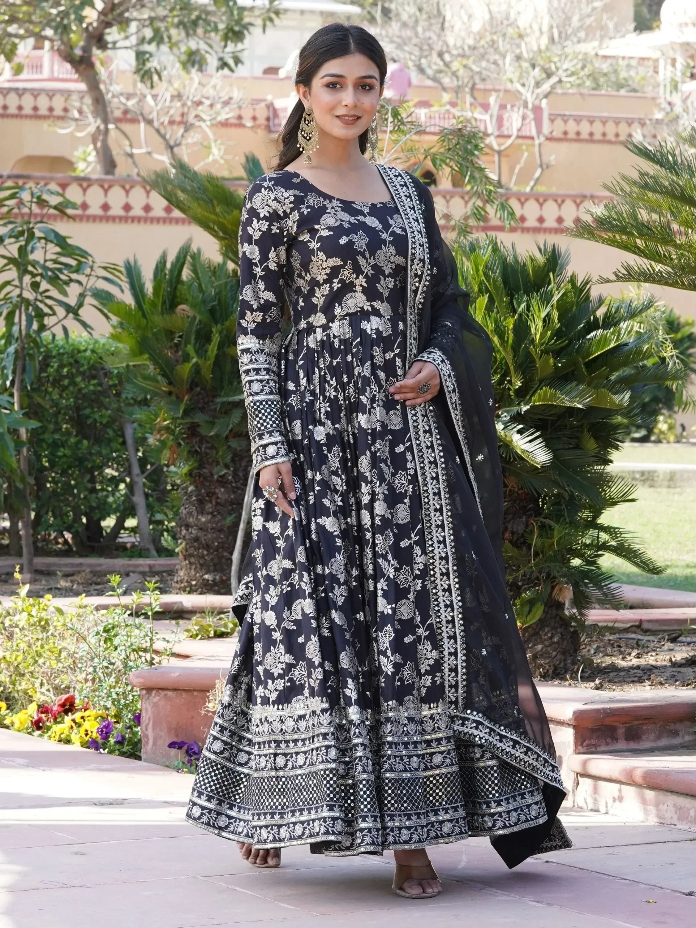 Woman in a black embroidered Anarkali suit with dupatta, outdoor garden setting, Indian ethnic wear