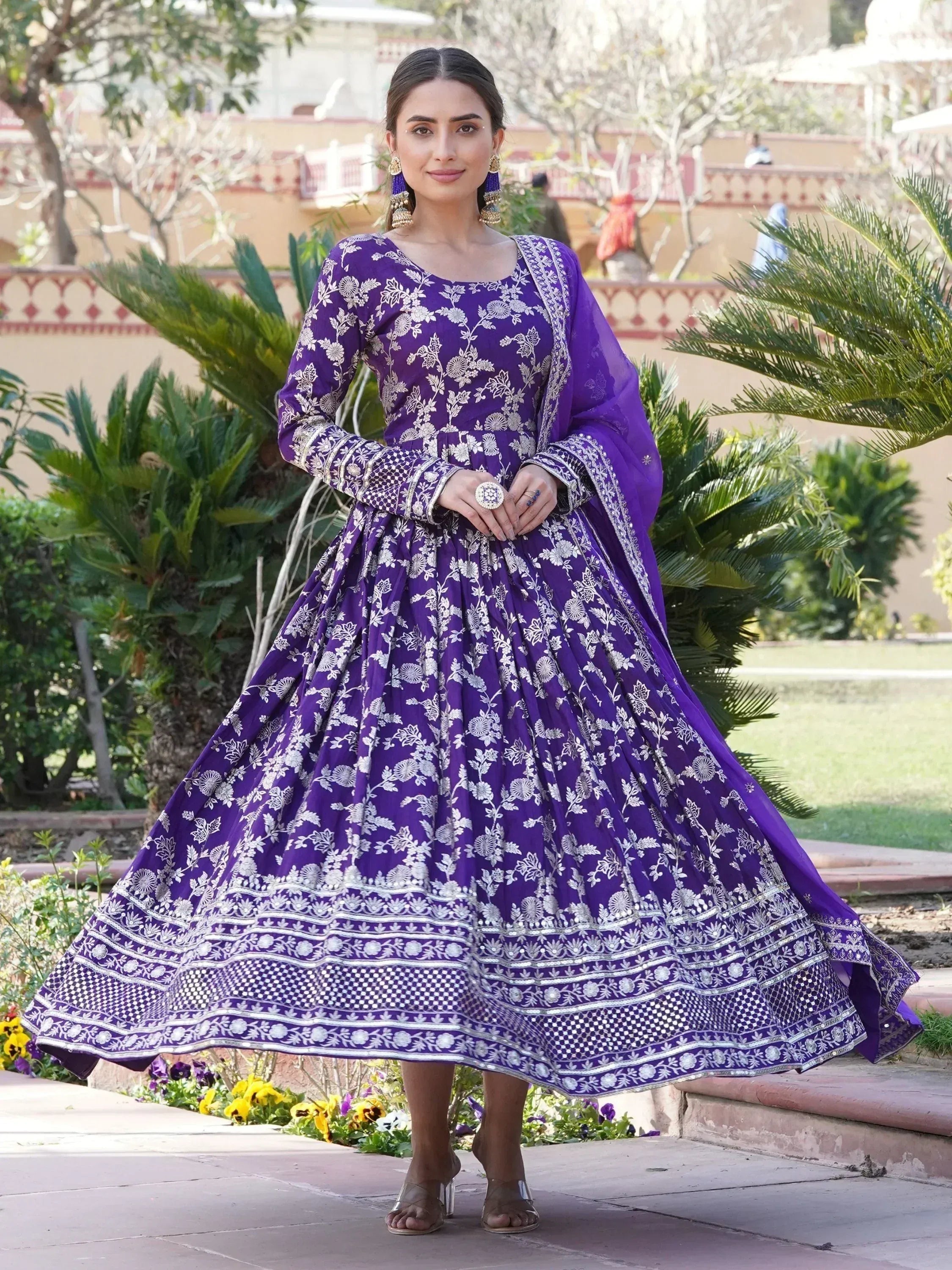Woman in purple embroidered Anarkali ethnic gown with dupatta, outdoor garden setting