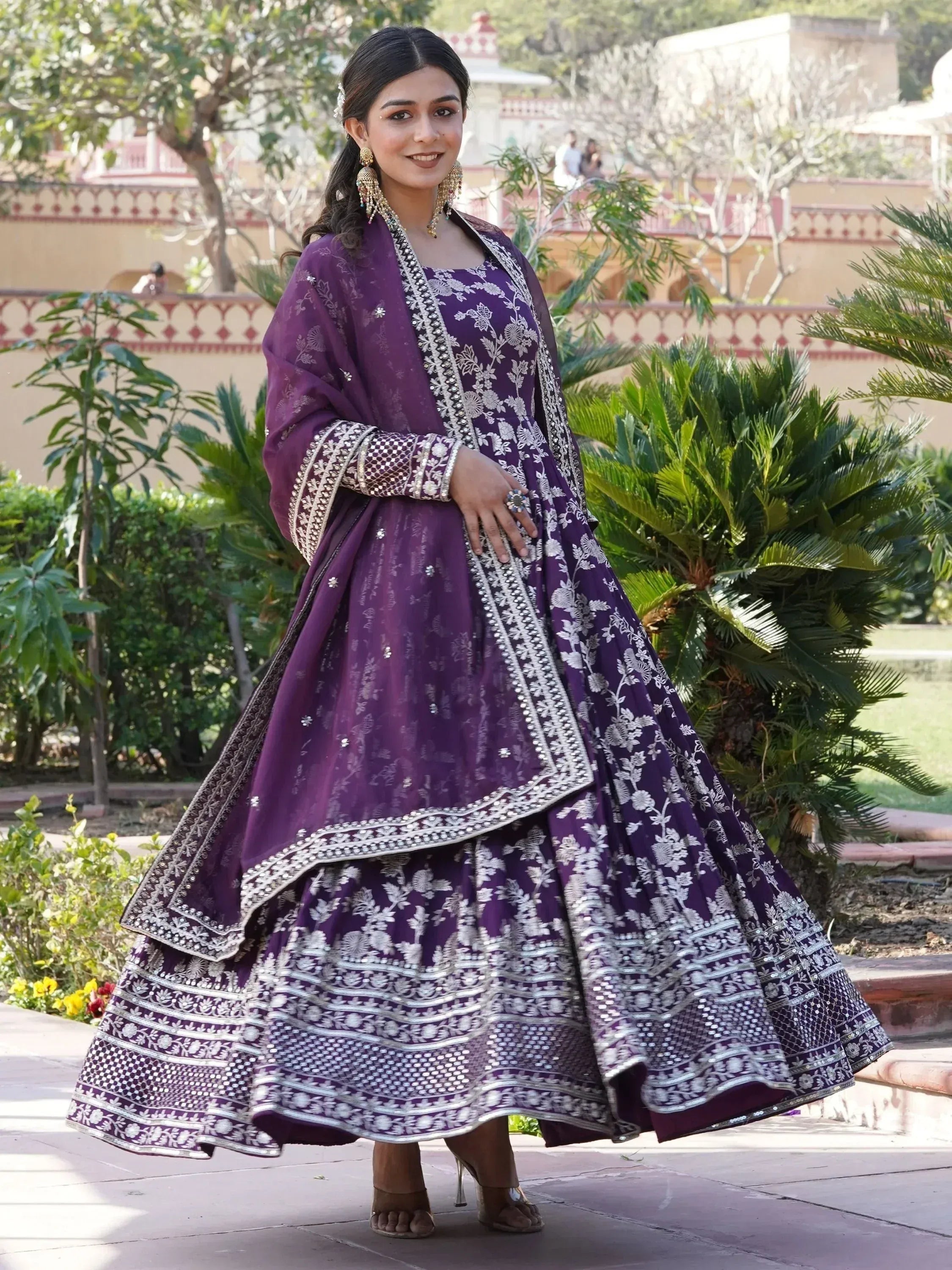 Woman in outdoor garden wearing wine purple embroidered lehenga choli with dupatta
