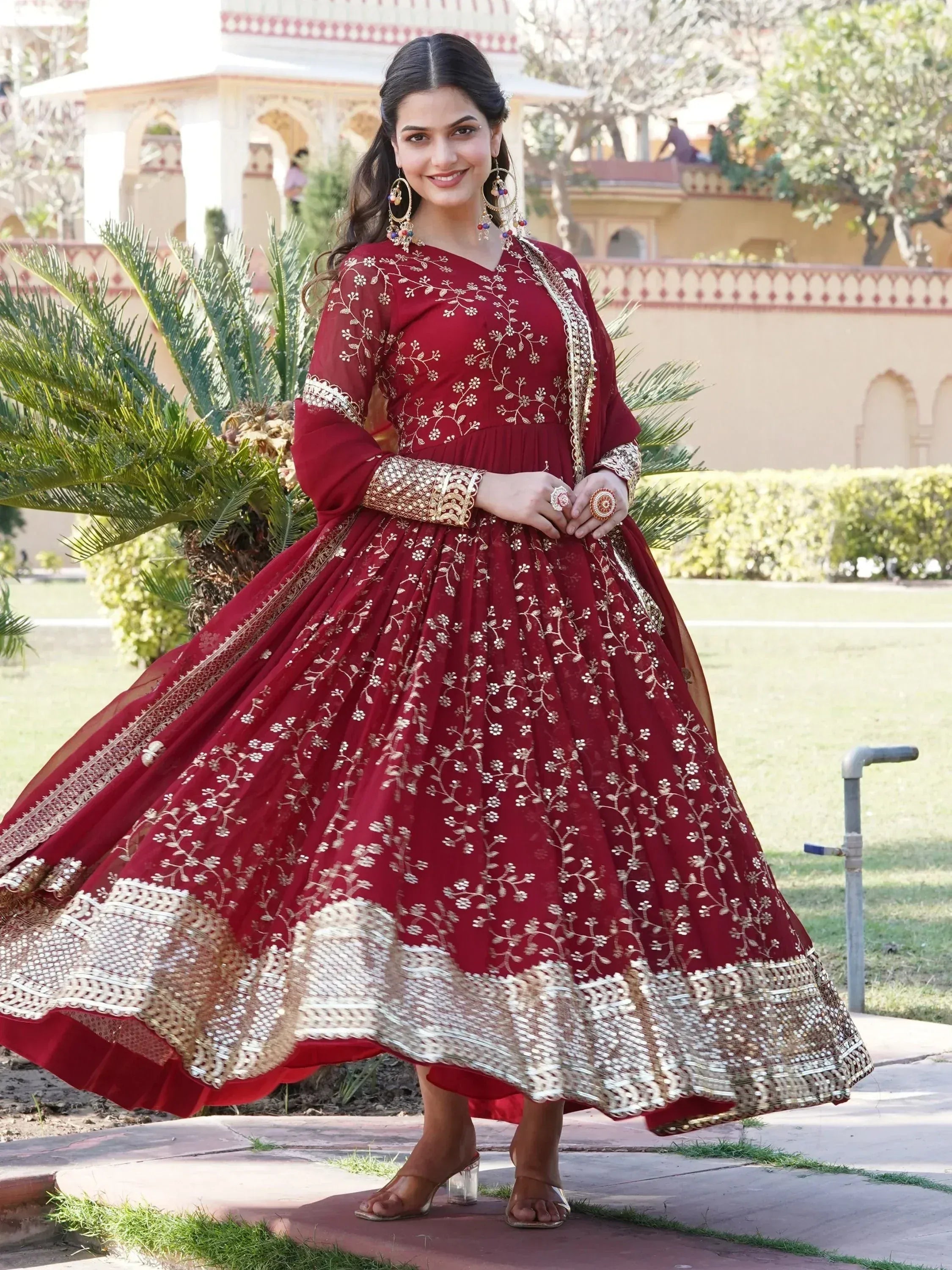 Red embroidered ethnic gown with gold floral work, perfect for Indian weddings and festive occasions.