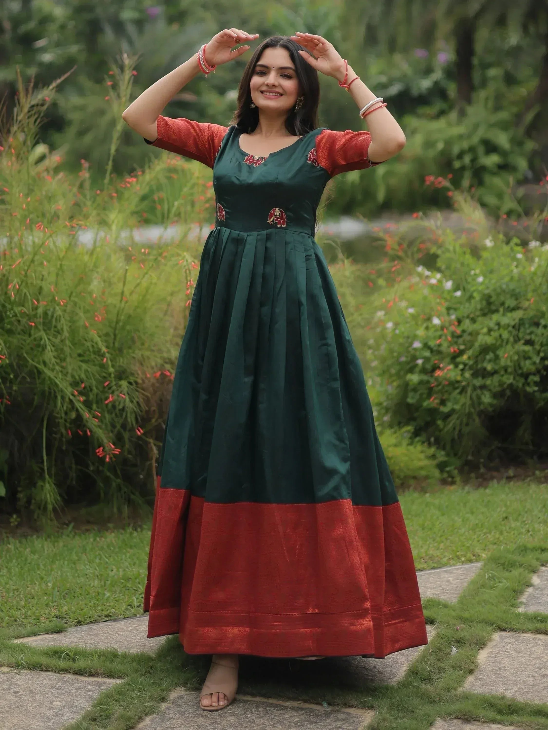Woman in green and red ethnic gown with elephant embroidery, perfect for Indian festive occasions