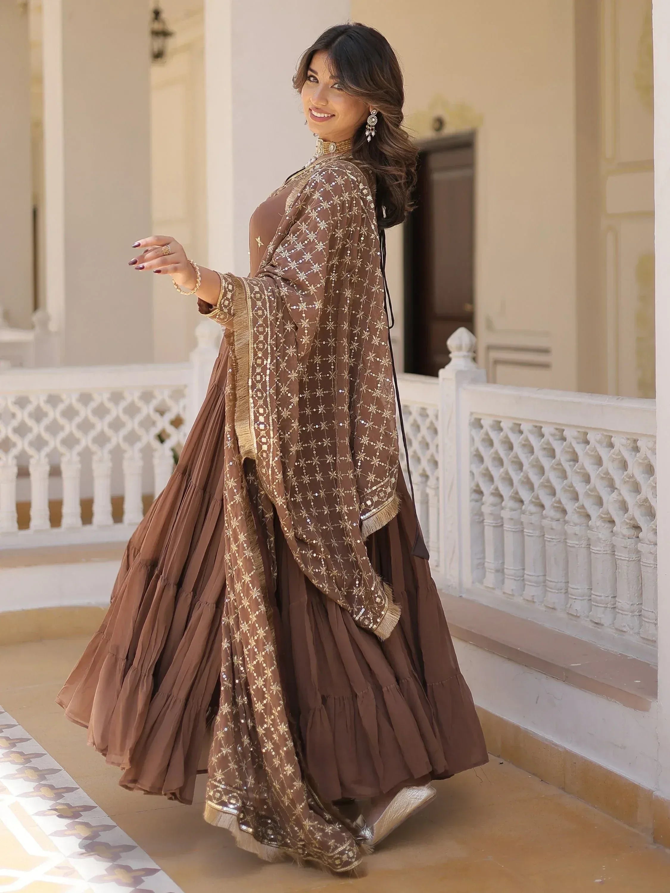 Brown designer lehenga choli with gold embroidery and sheer dupatta, perfect for Indian ethnic occasions.