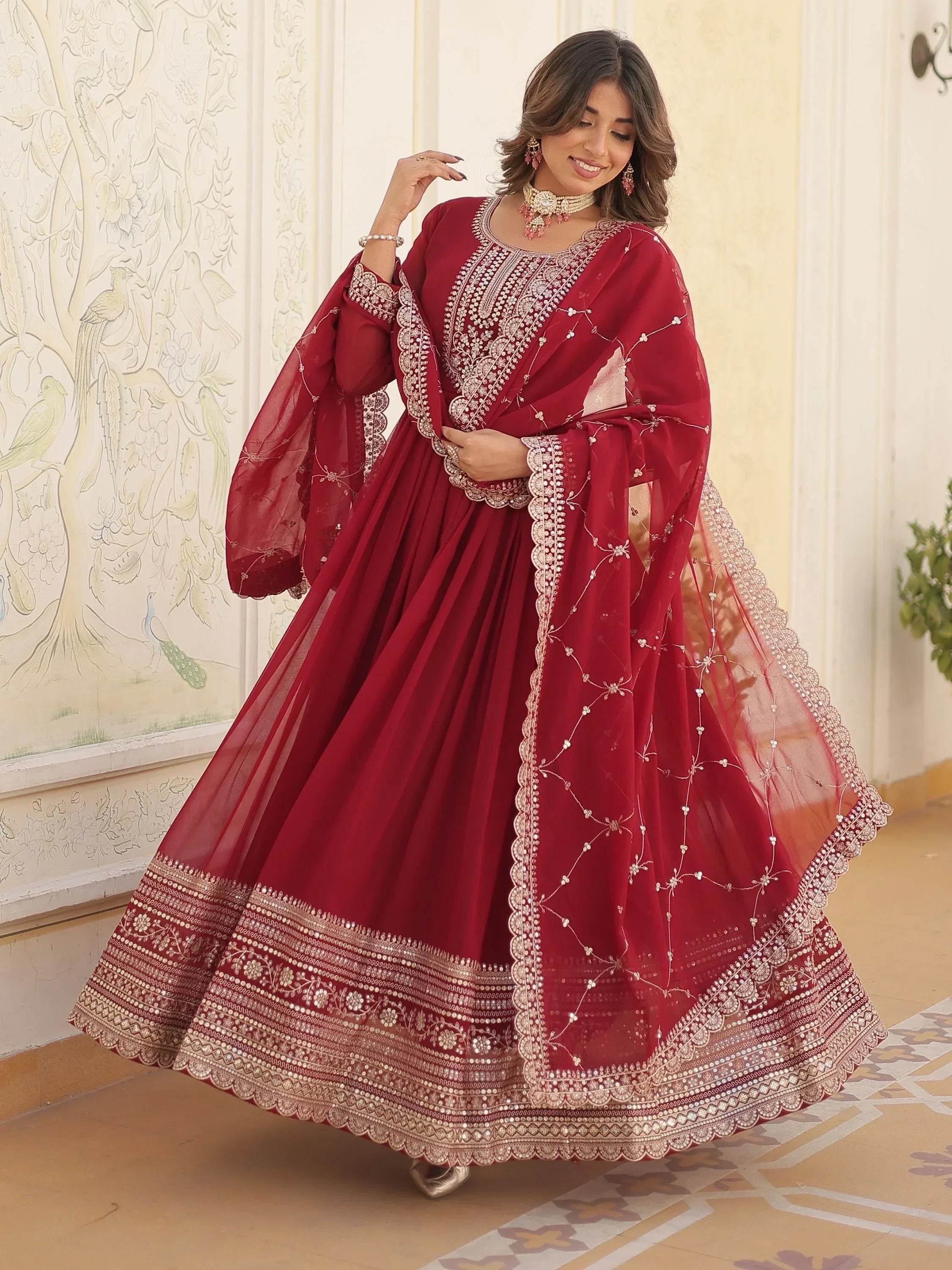 Woman in maroon embroidered ethnic gown with dupatta and traditional jewelry