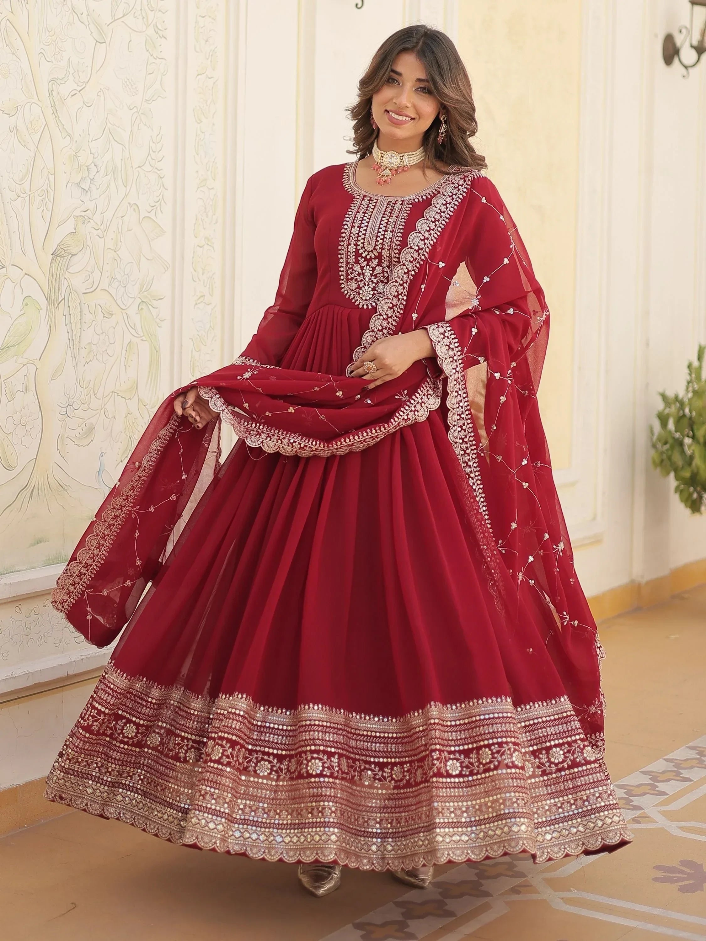Woman in a maroon embroidered anarkali gown with dupatta, Indian ethnic wear.