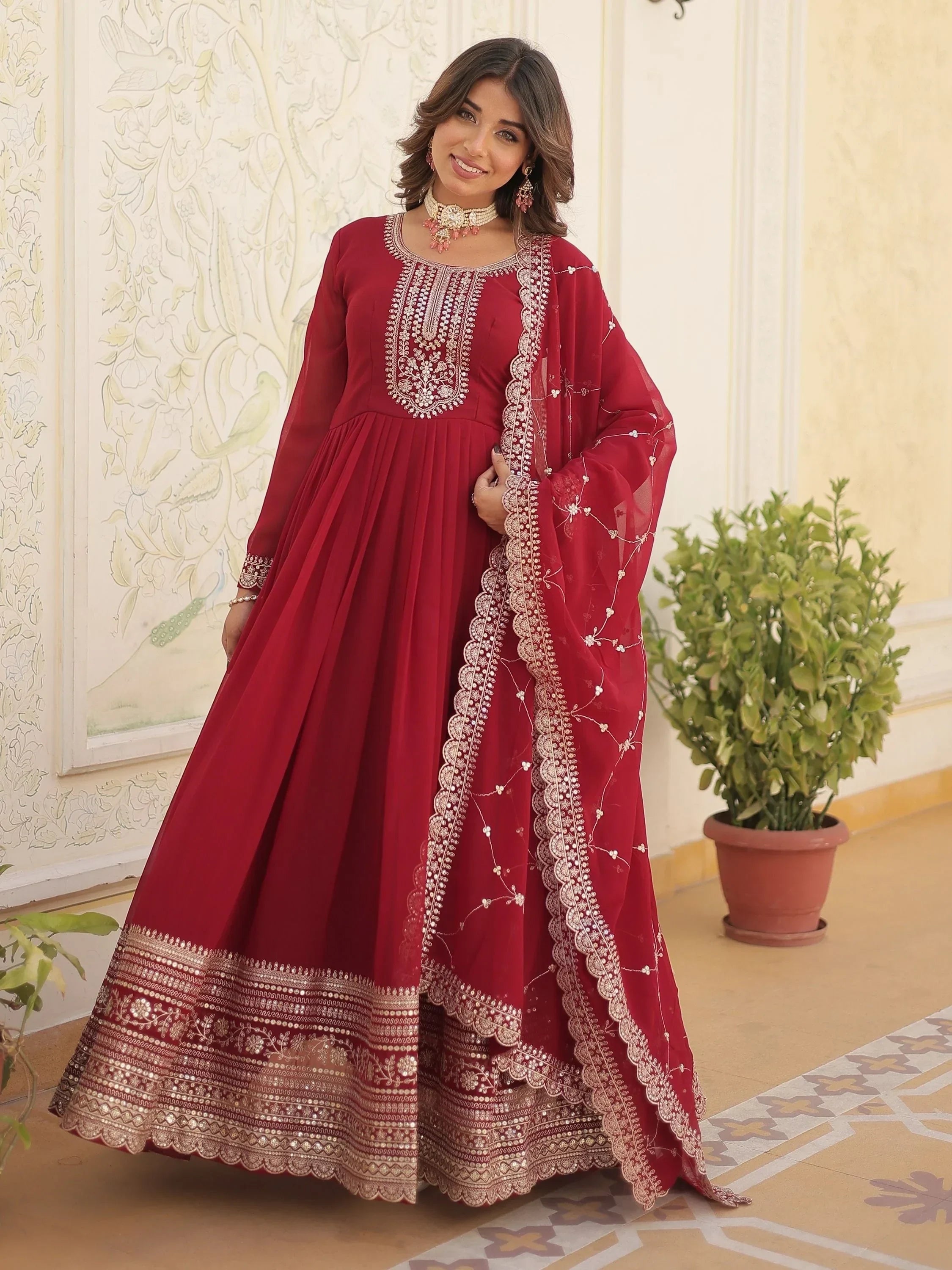 Woman wearing maroon embroidered Anarkali suit with dupatta and traditional jewelry