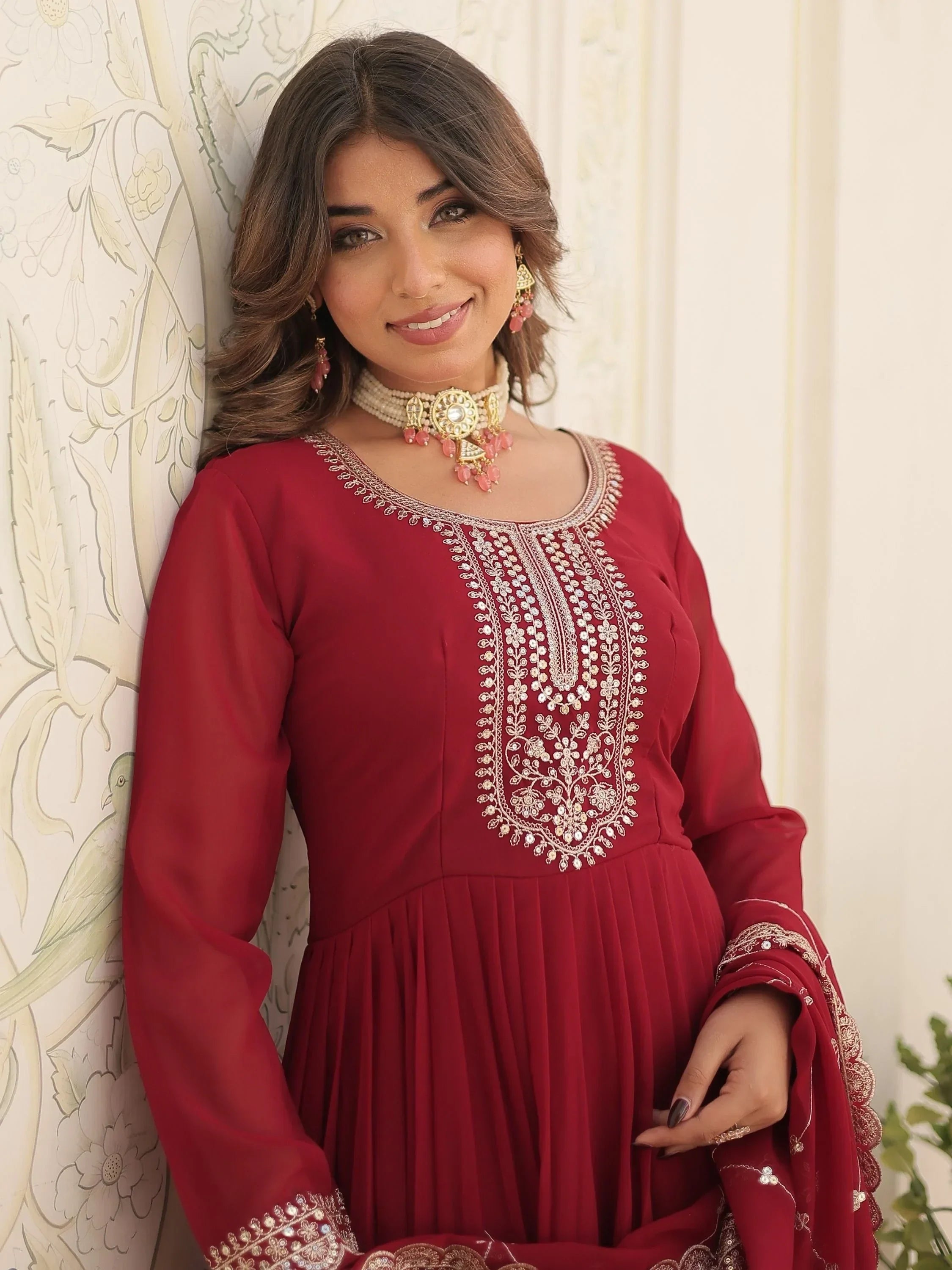 Woman in maroon embroidered salwar kameez with long sleeves and statement jewelry