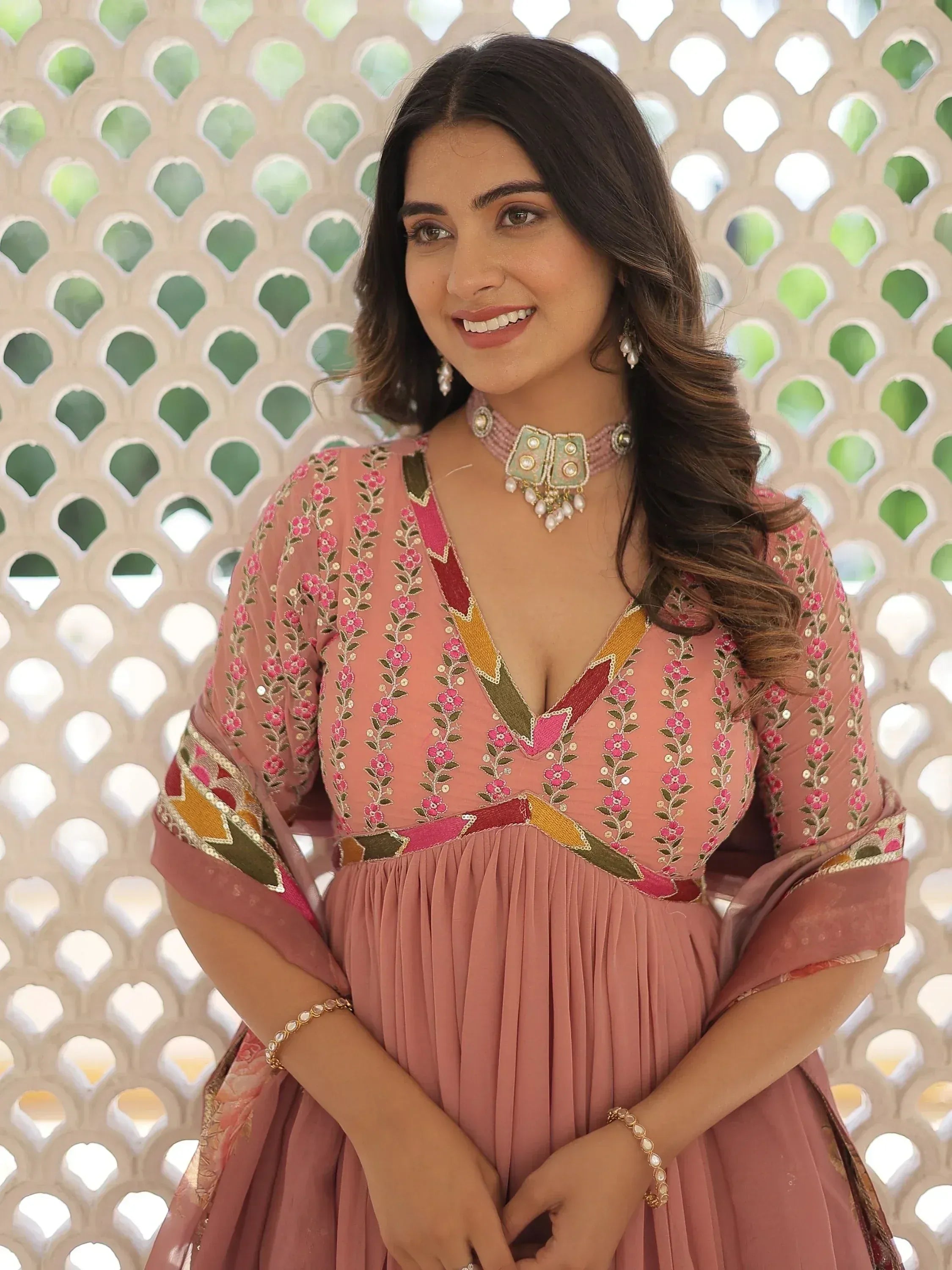 Woman in pink embroidered ethnic gown with floral design, perfect for Indian occasions