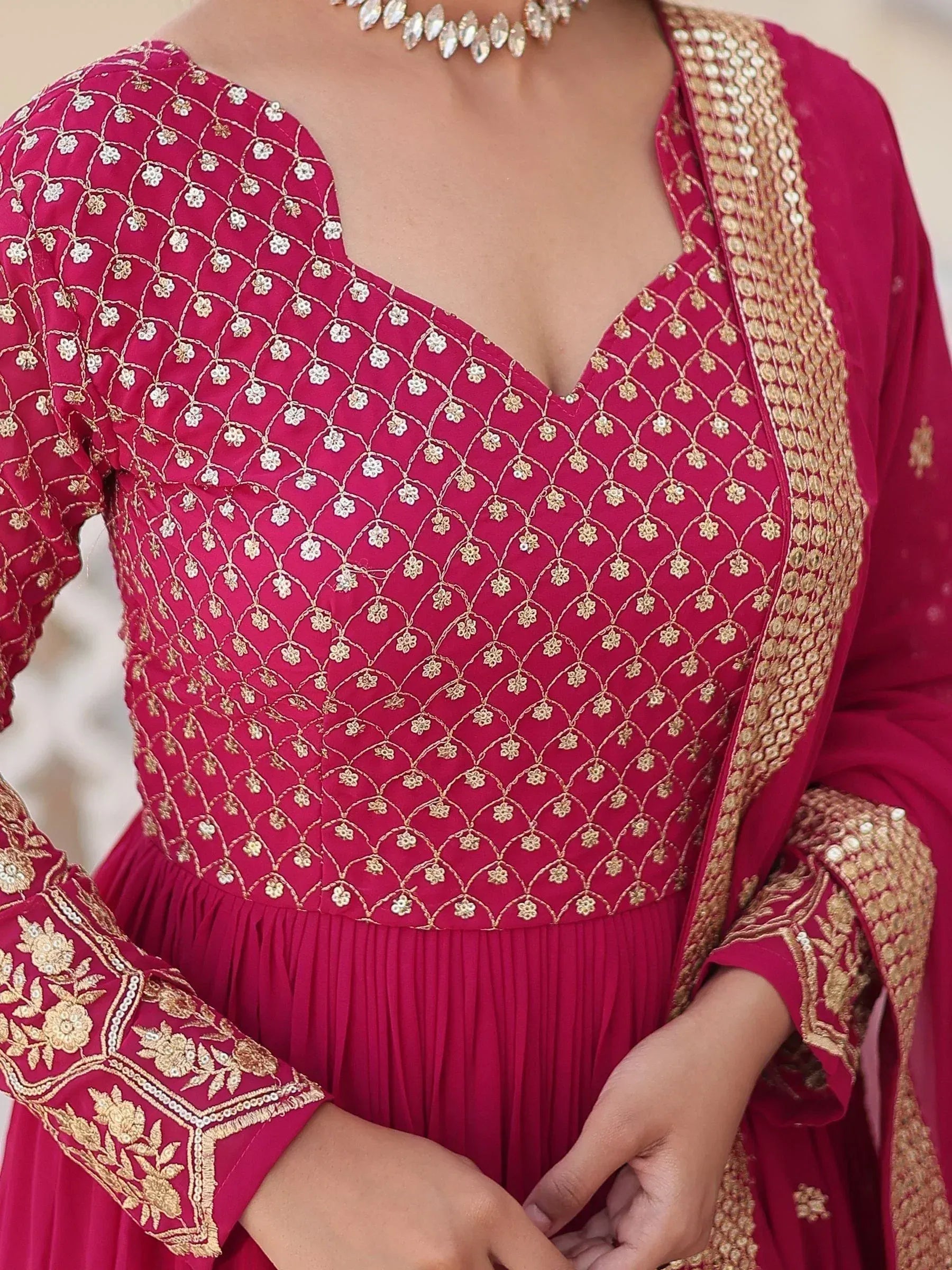 Pink ethnic gown with gold floral embroidery and pleated skirt, perfect for Indian weddings or festivals.