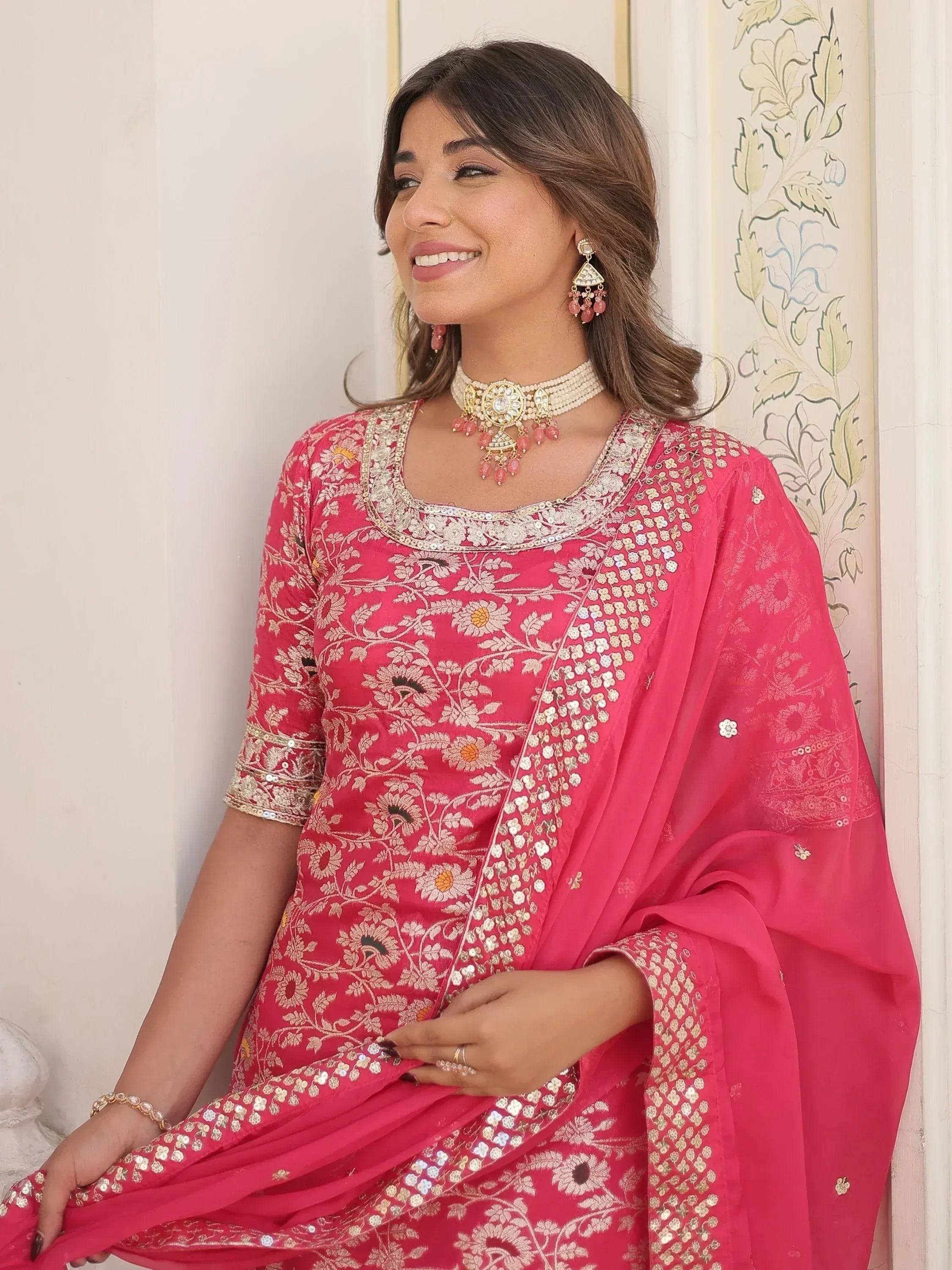 Pink floral embroidered salwar kameez with gold detailing and matching dupatta, styled with traditional jewelry