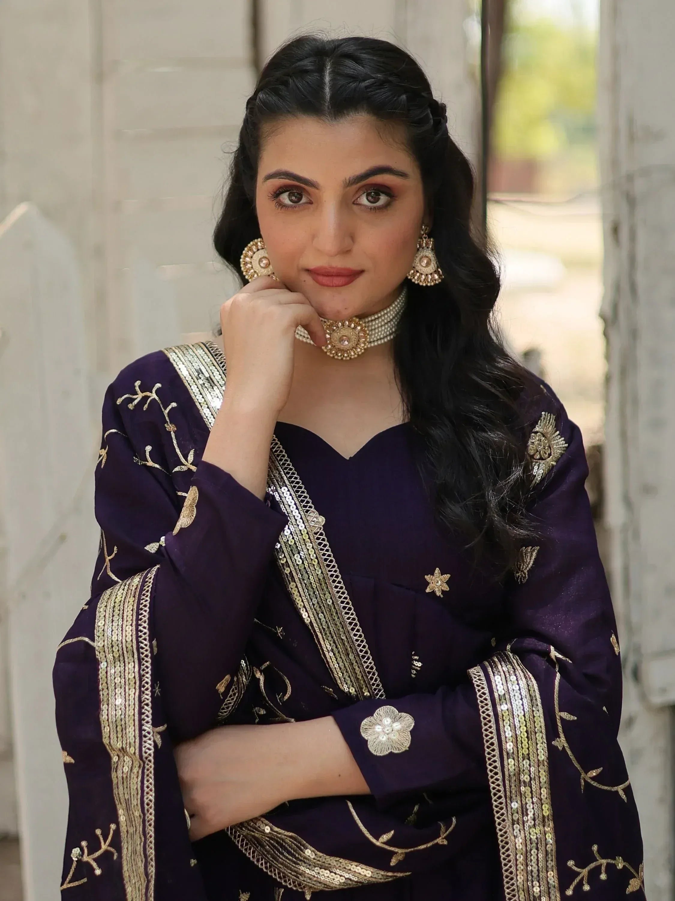 Elegant purple ethnic gown with gold embroidery and sequin detailing, paired with traditional jewelry.