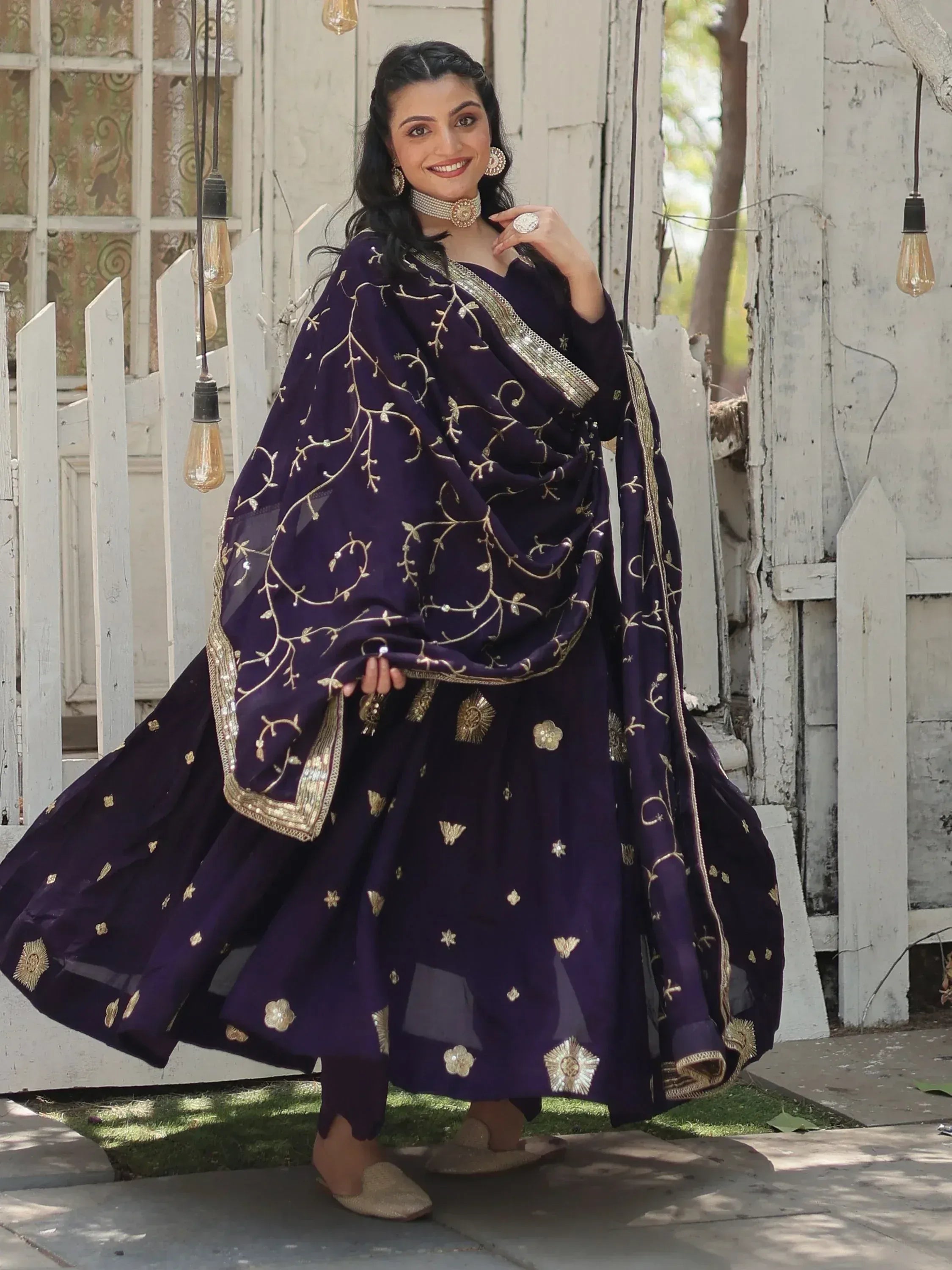 Woman in purple embroidered salwar kameez with gold detailing, perfect for Indian ethnic wear occasions.