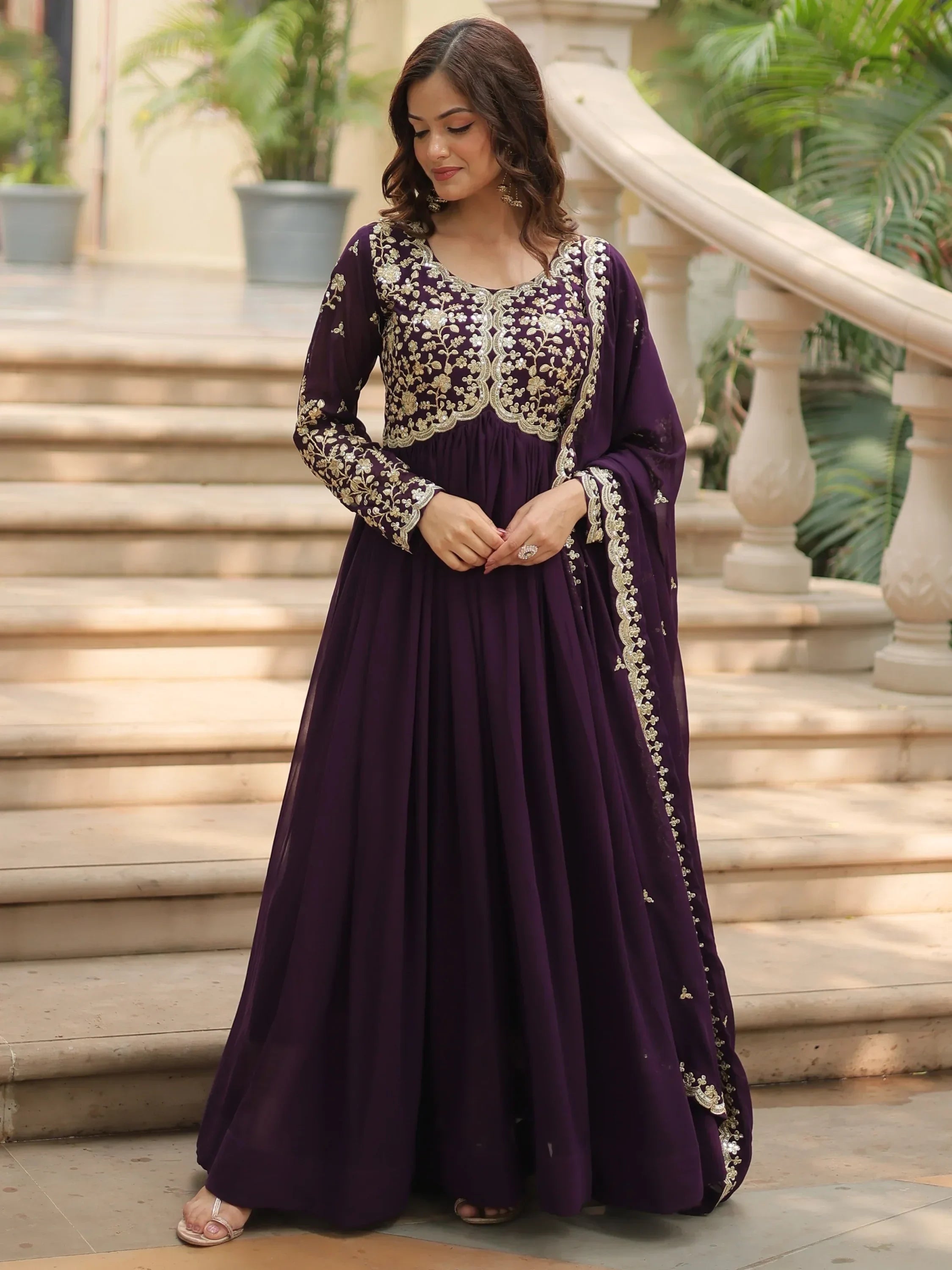 Woman in a purple embroidered Anarkali gown with gold floral detailing, outdoor setting