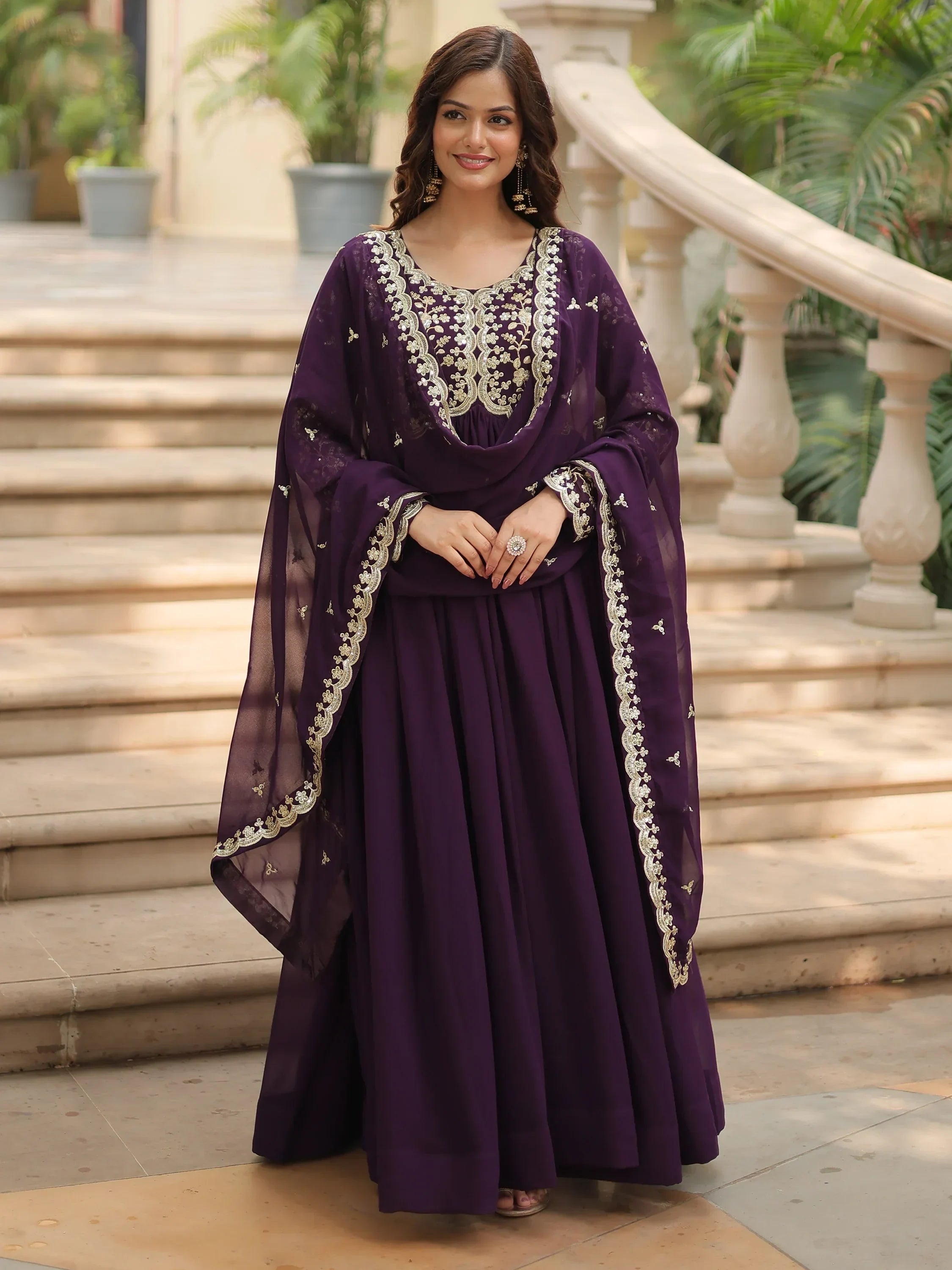 Woman in purple ethnic gown with gold embroidery standing on outdoor steps