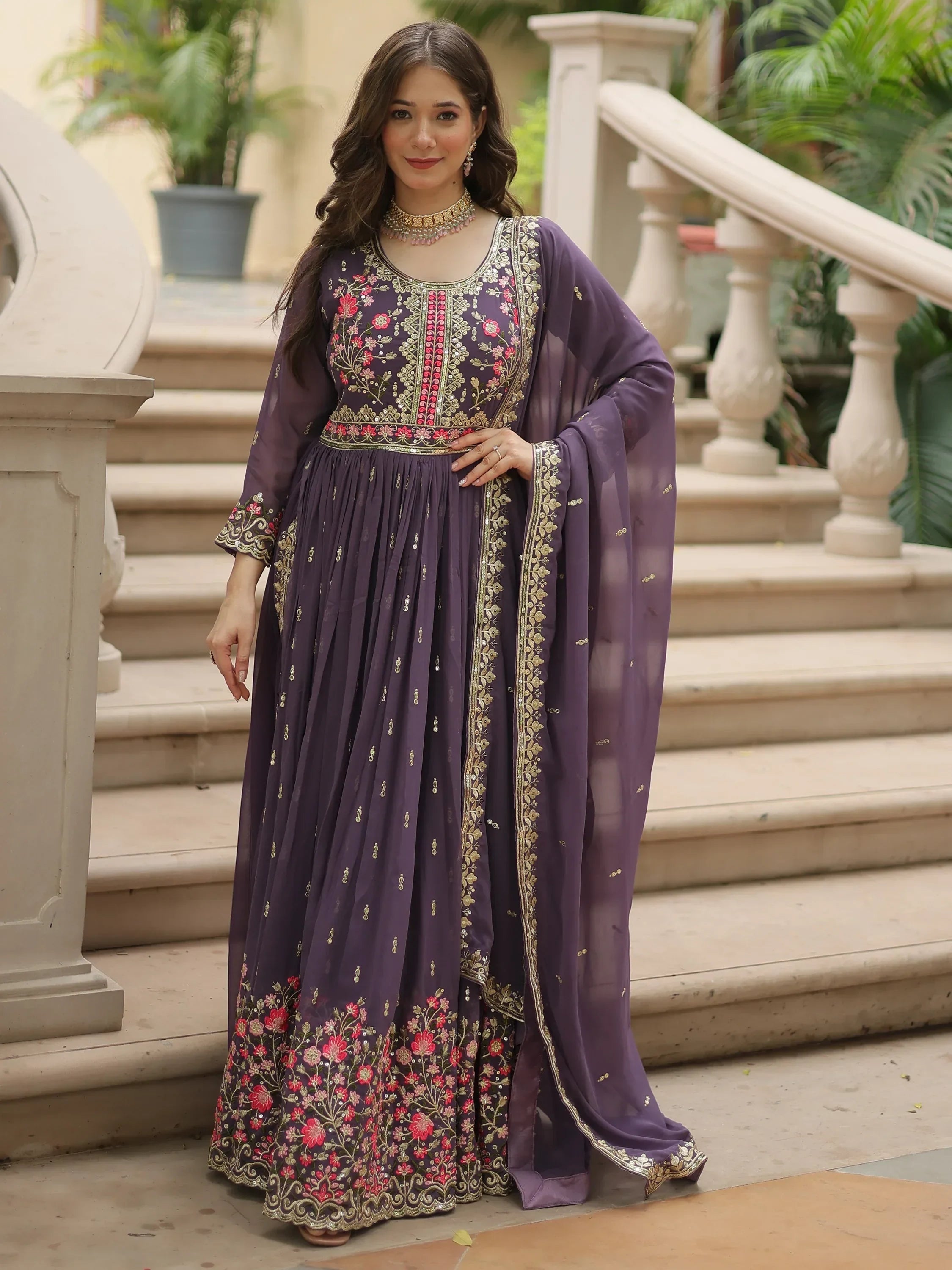 Woman wearing purple embroidered Indian ethnic gown with floral detailing and dupatta
