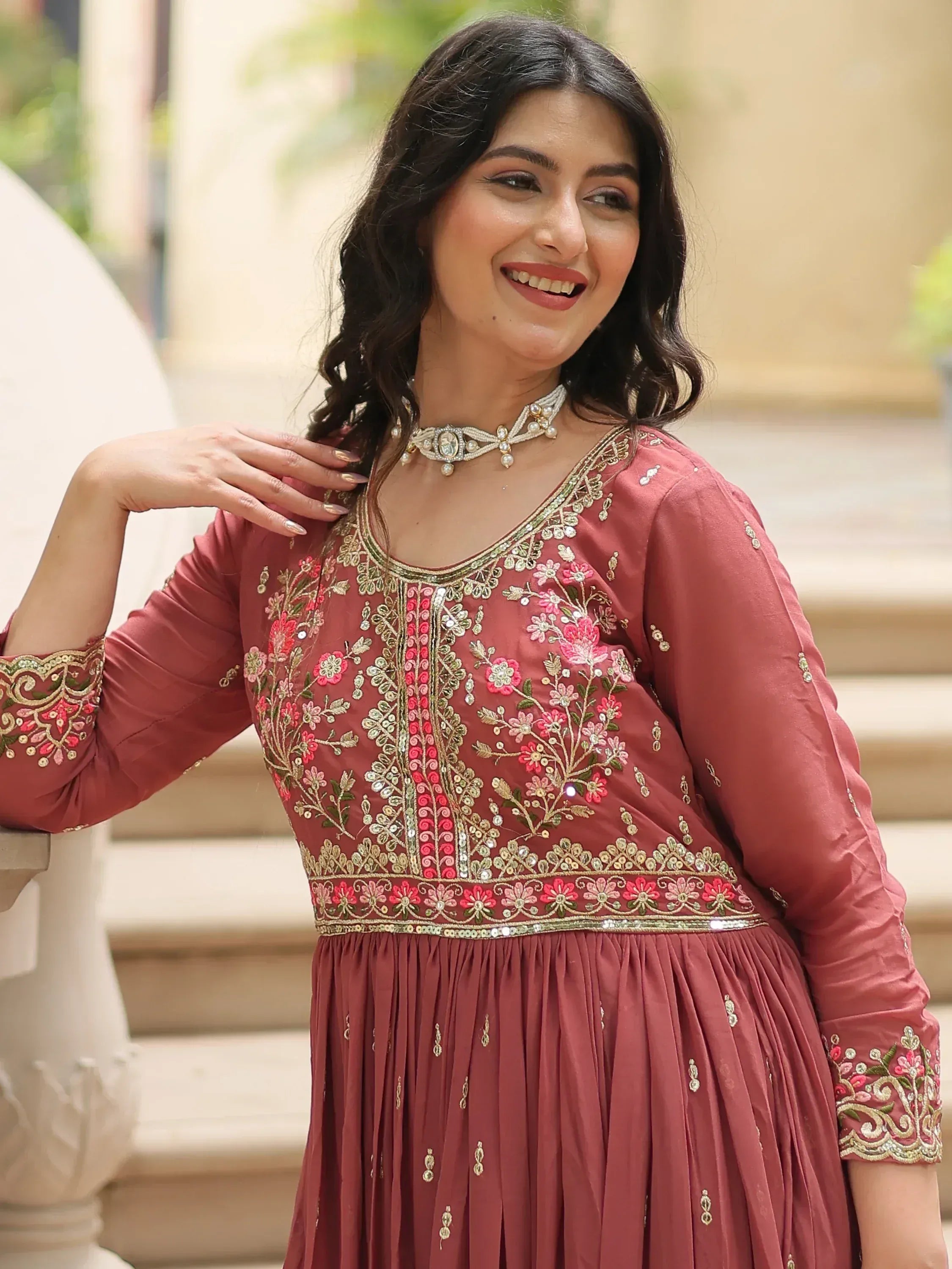 Woman in maroon embroidered ethnic gown with floral detailing, perfect for Indian festive occasions