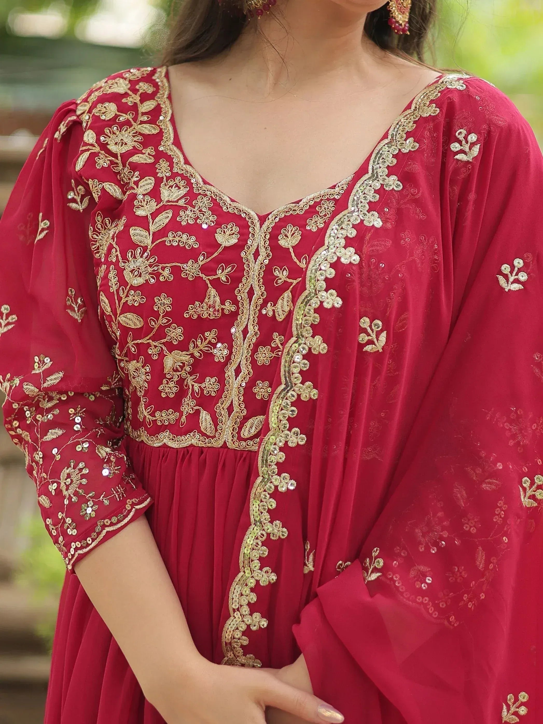 Red ethnic gown with gold floral embroidery and sequin detailing, perfect for Indian occasions.