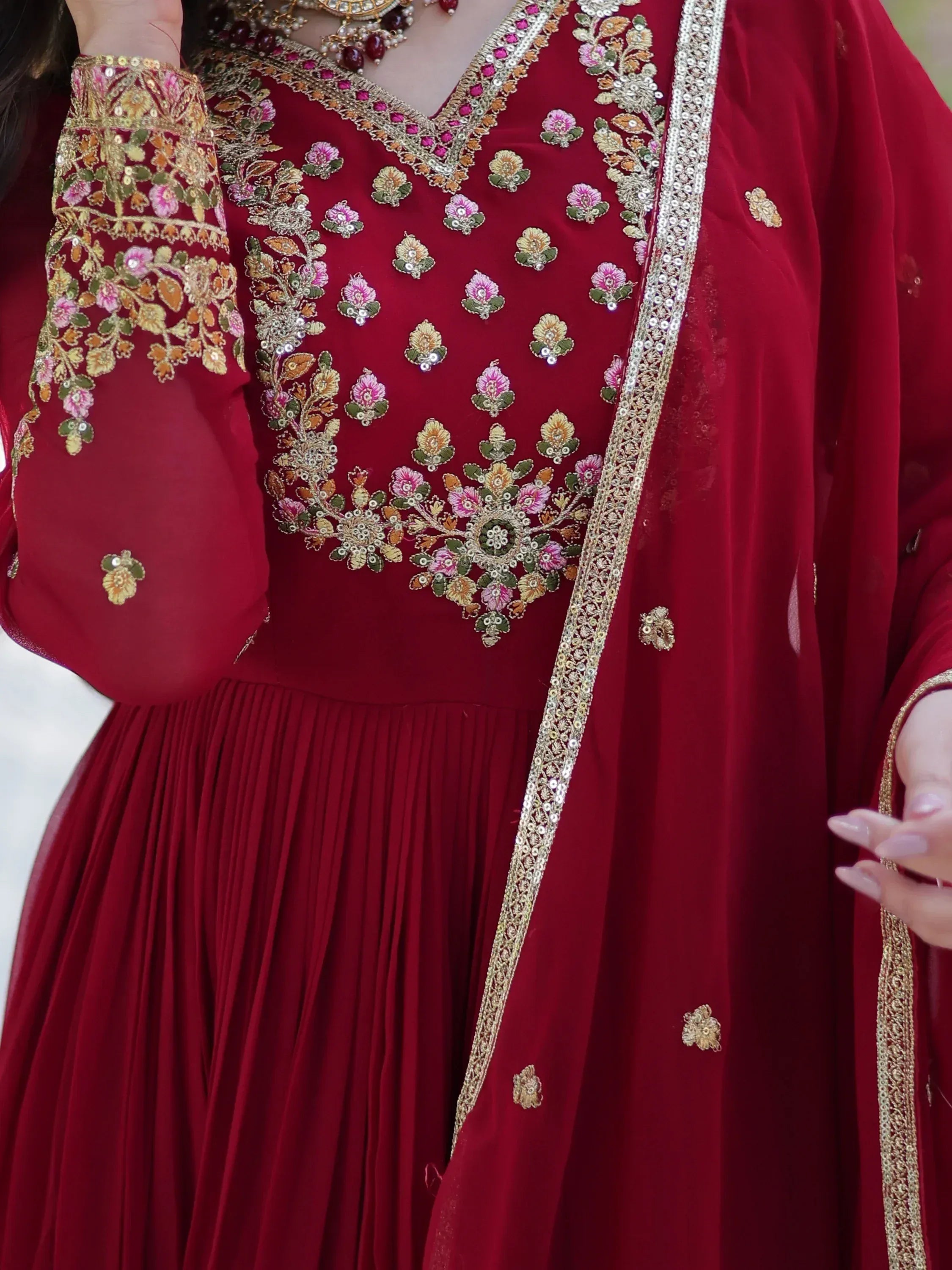 Red velvet ethnic gown with floral embroidery and gold detailing, perfect for Indian weddings or festive occasions.
