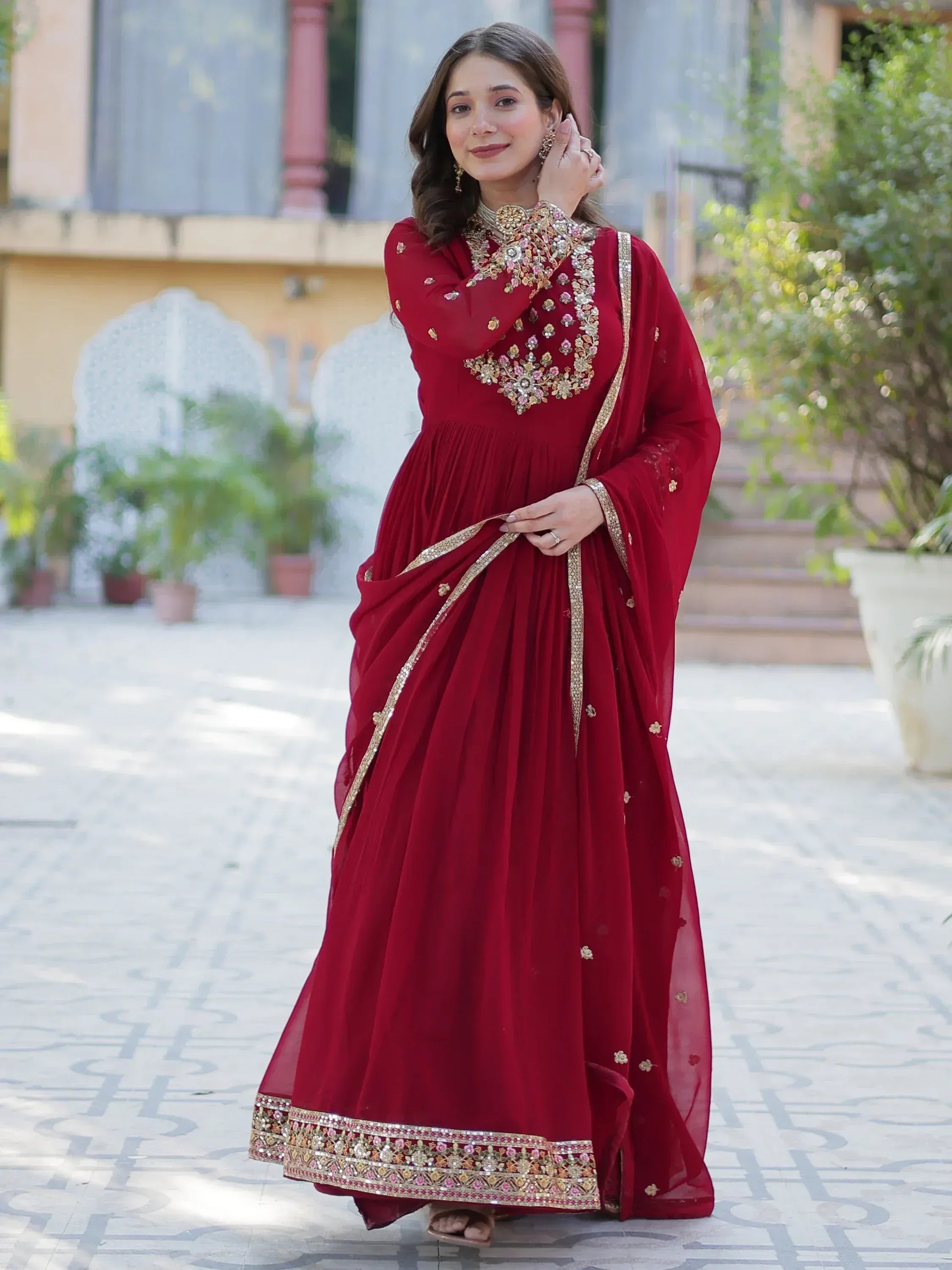 Elegant maroon ethnic gown with floral embroidery and gold trim, perfect for Indian celebrations.