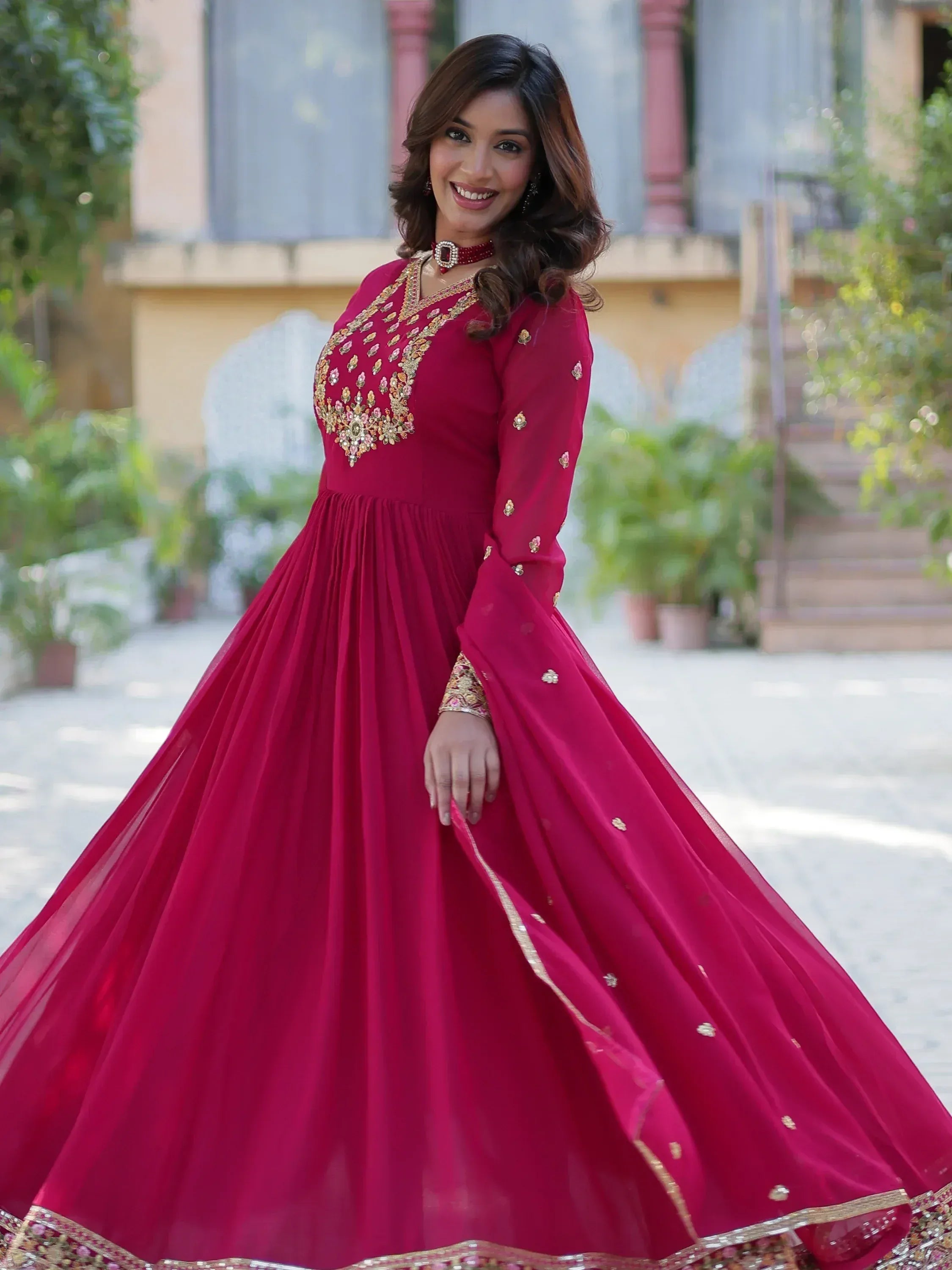 Woman in maroon ethnic gown with gold embroidery, perfect for Indian weddings and festive occasions.