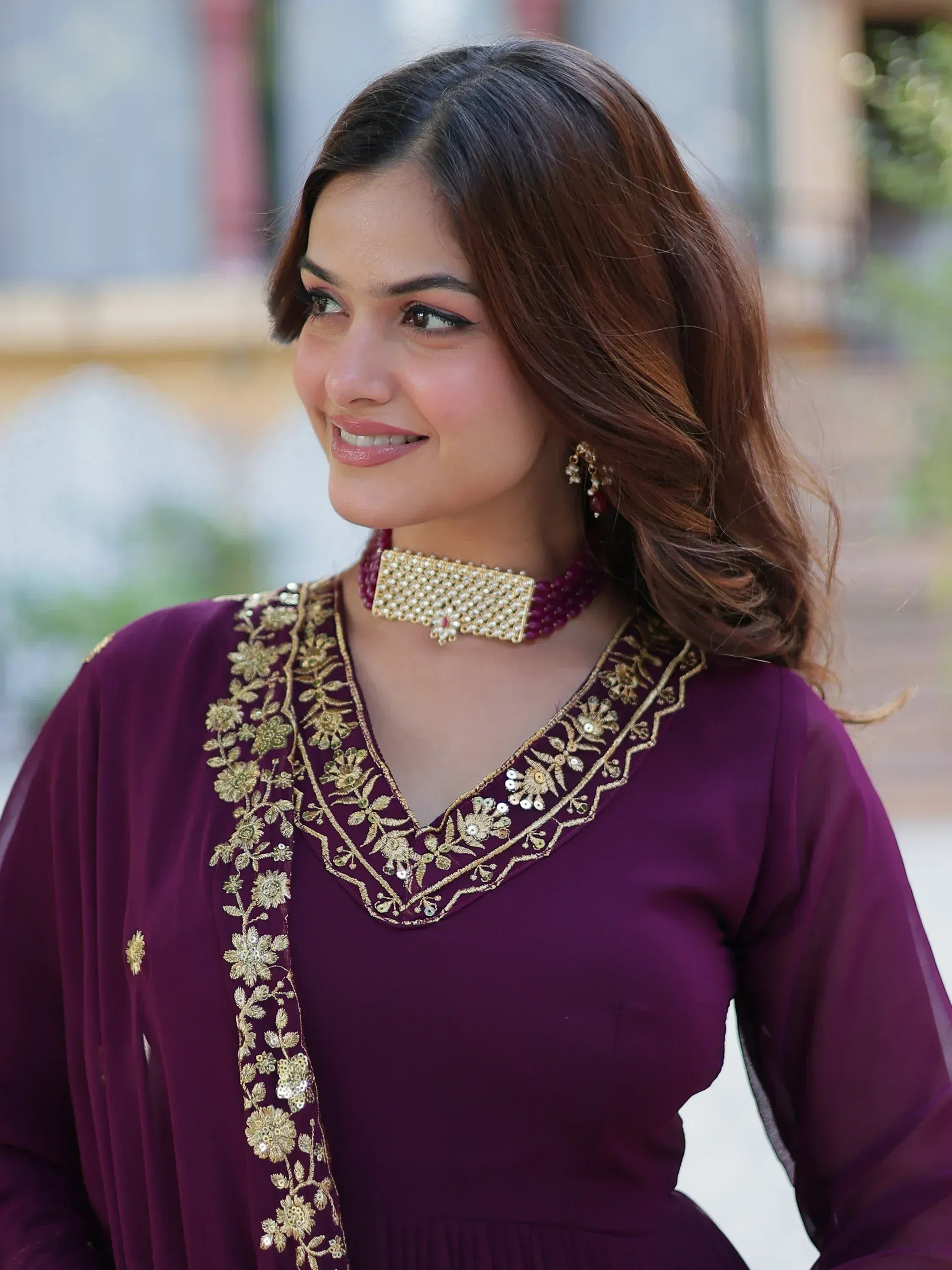 Woman in purple ethnic gown with gold embroidery and matching jewelry, perfect for Indian occasions
