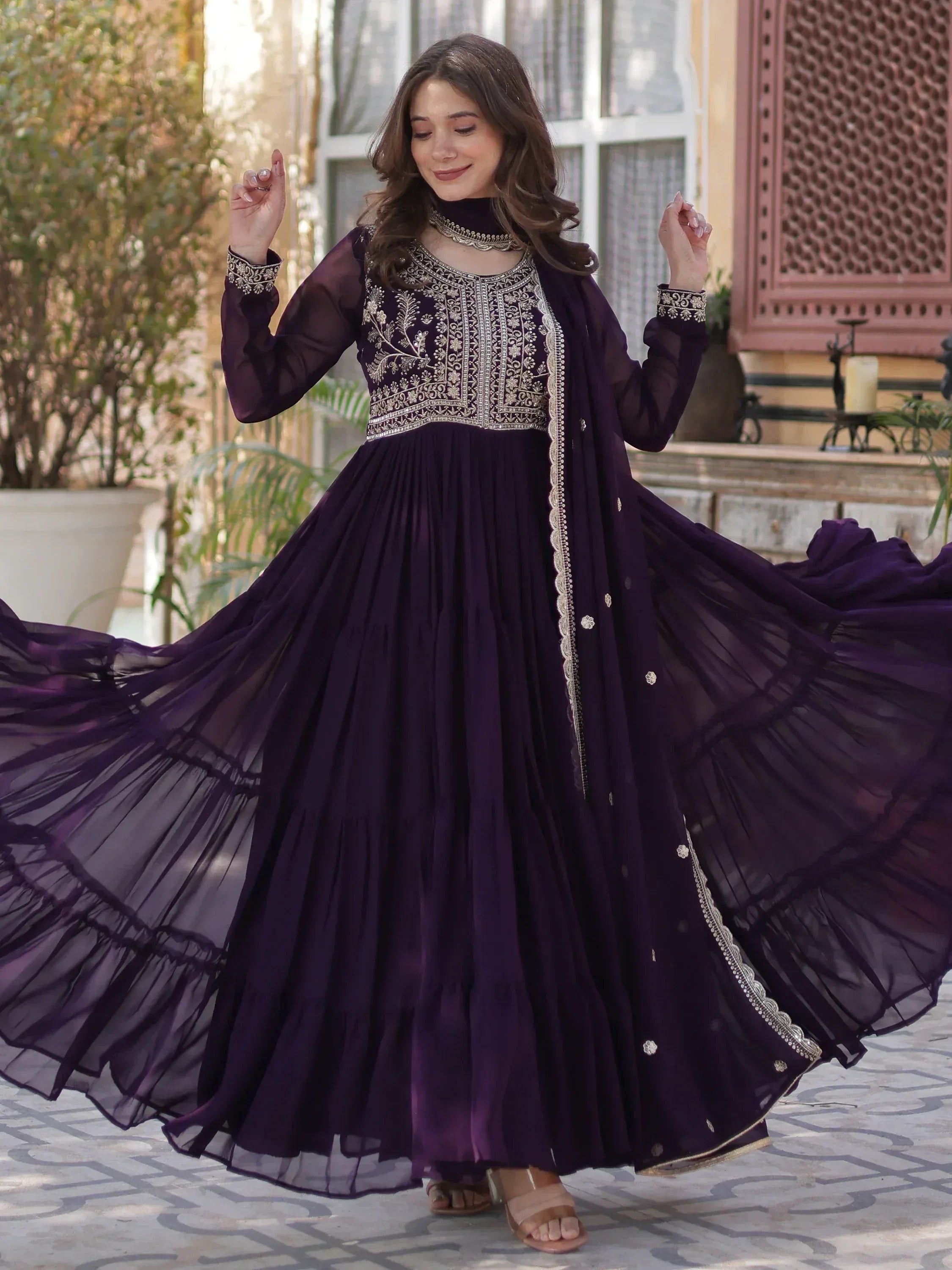 Elegant purple ethnic gown with gold embroidery, flowing pleated skirt, and sheer sleeves for festive occasions.