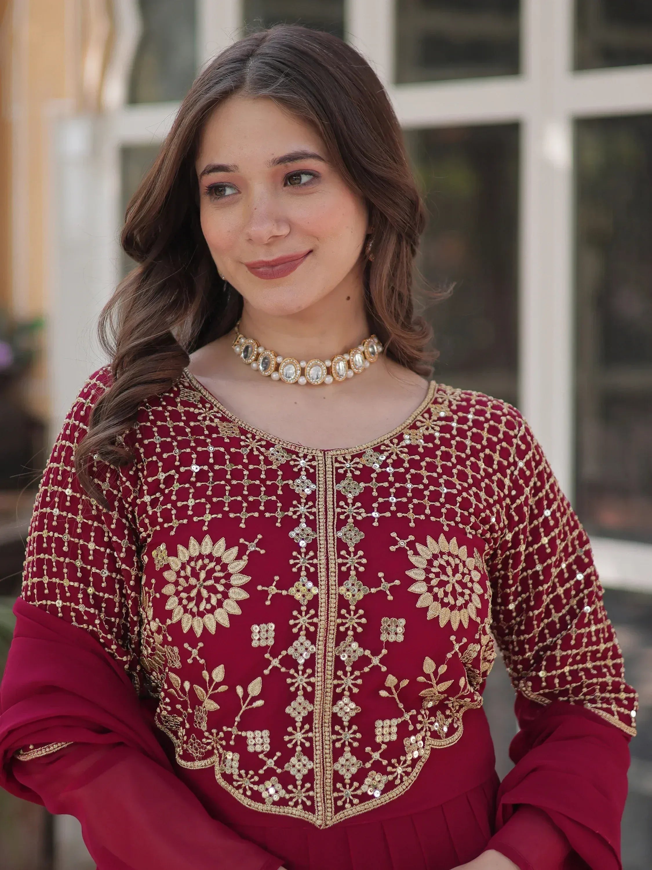 Maroon ethnic kurti with gold embroidery and floral designs, paired with a pearl necklace