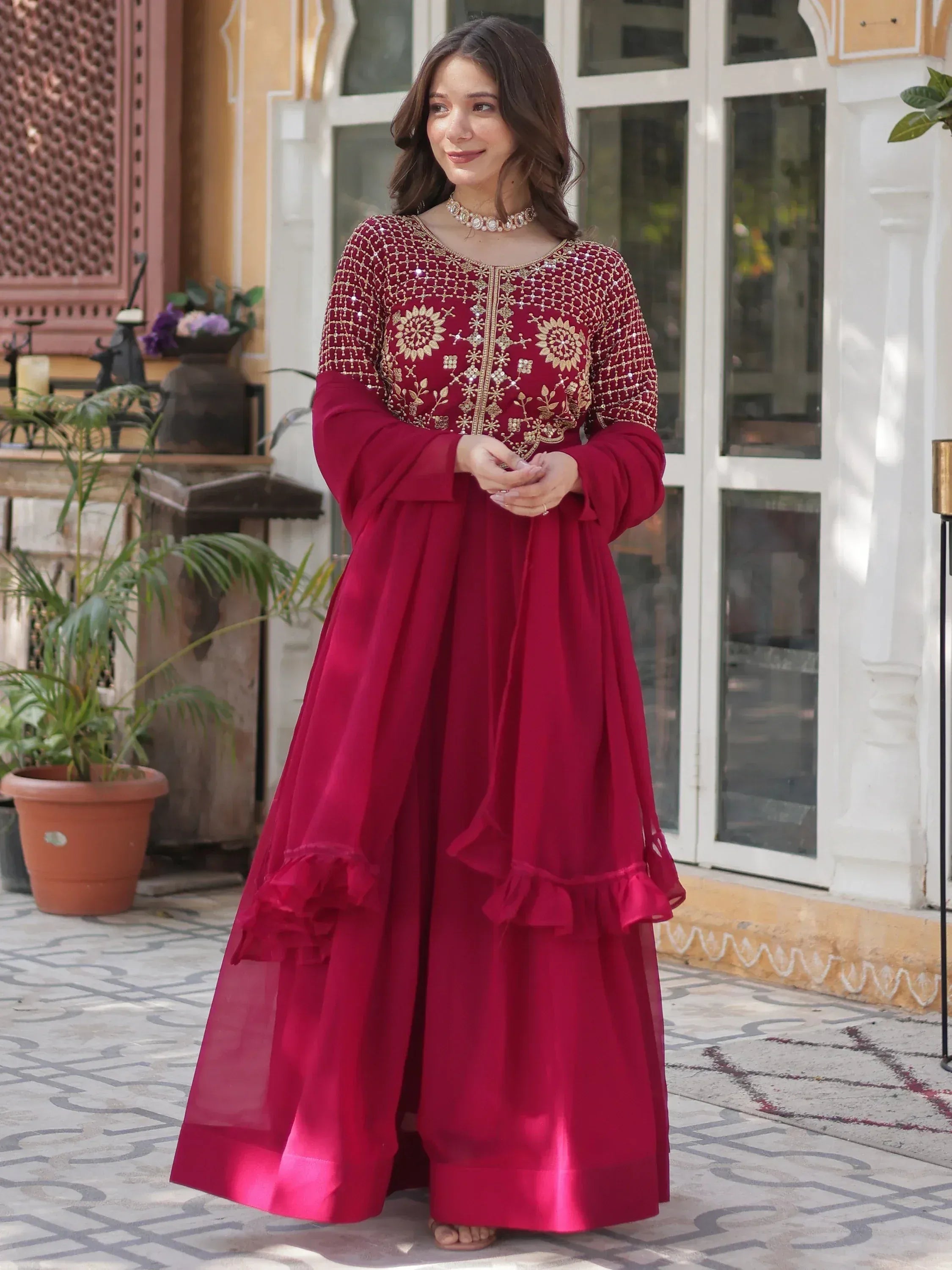 Maroon ethnic gown with gold embroidery and ruffle hem, perfect for Indian festive occasions