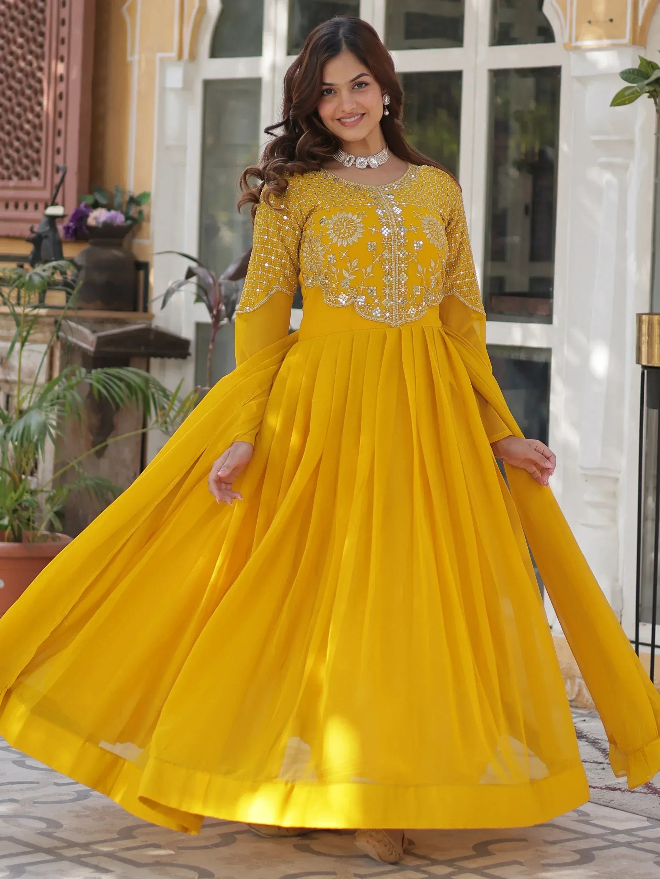 Yellow ethnic gown with floral embroidery and pleated skirt for festive occasions