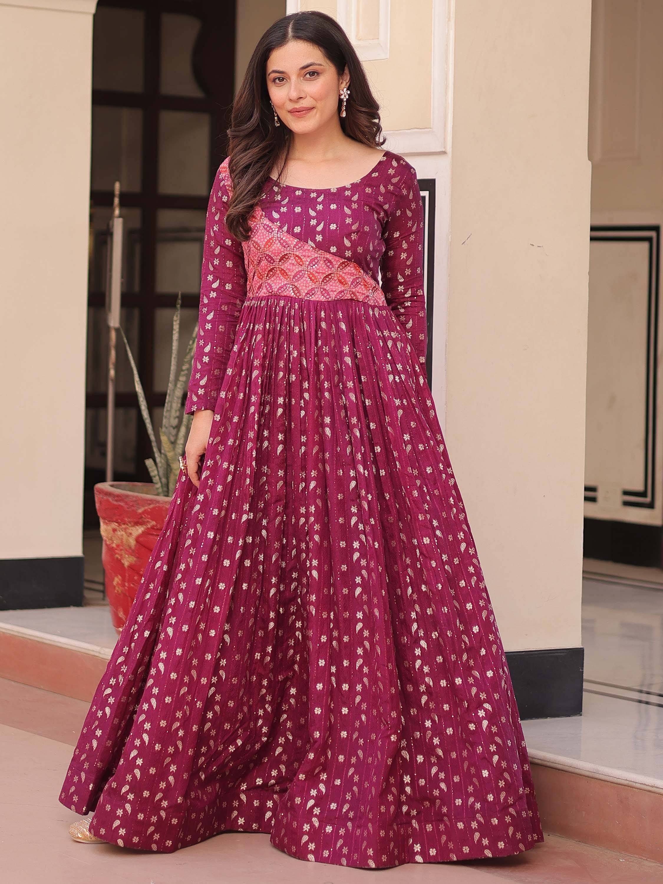Woman in a maroon printed ethnic gown with gold motifs and long sleeves, standing outdoors