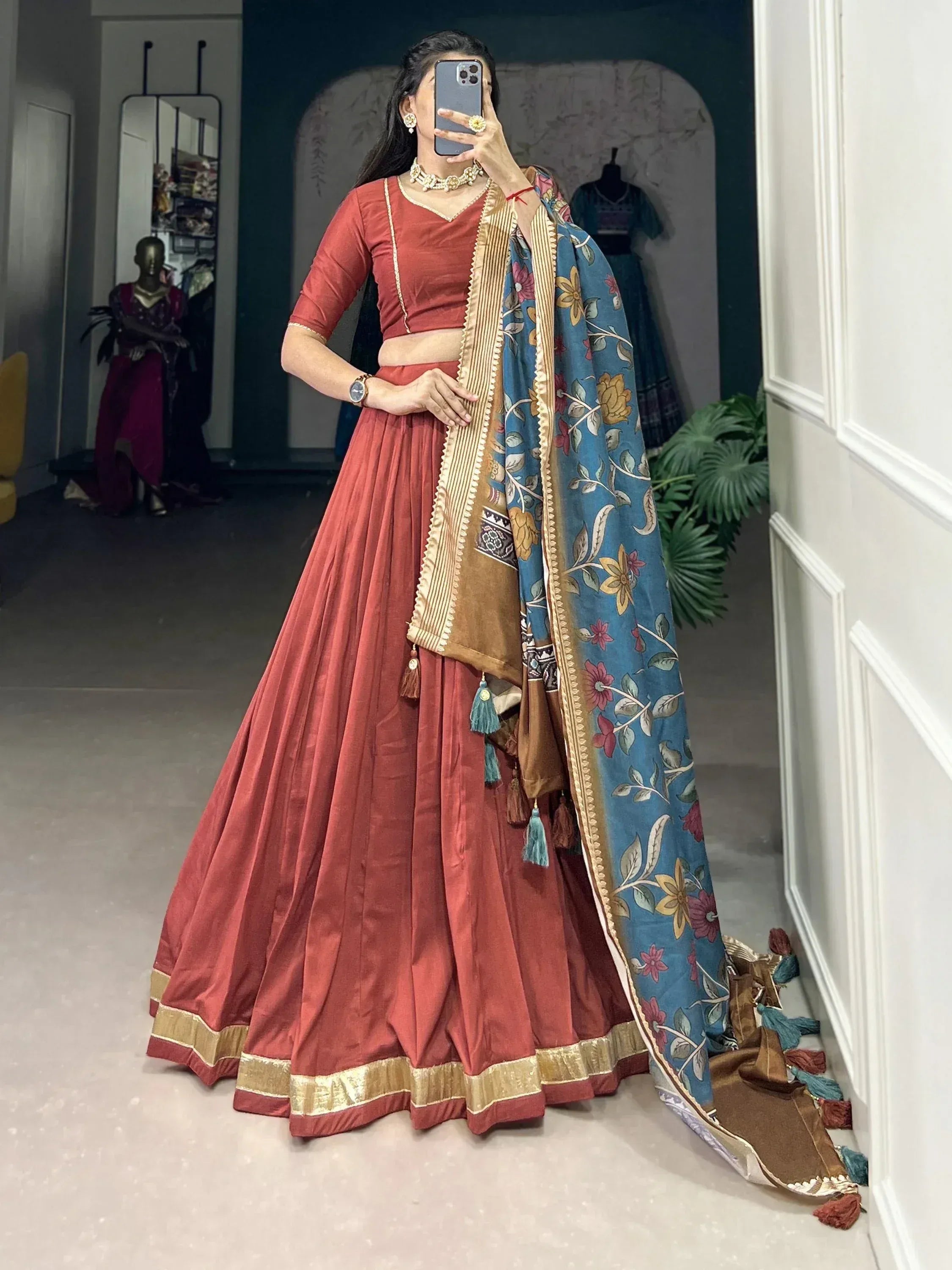Woman in red lehenga choli with floral dupatta, ethnic Indian wear for festive occasions