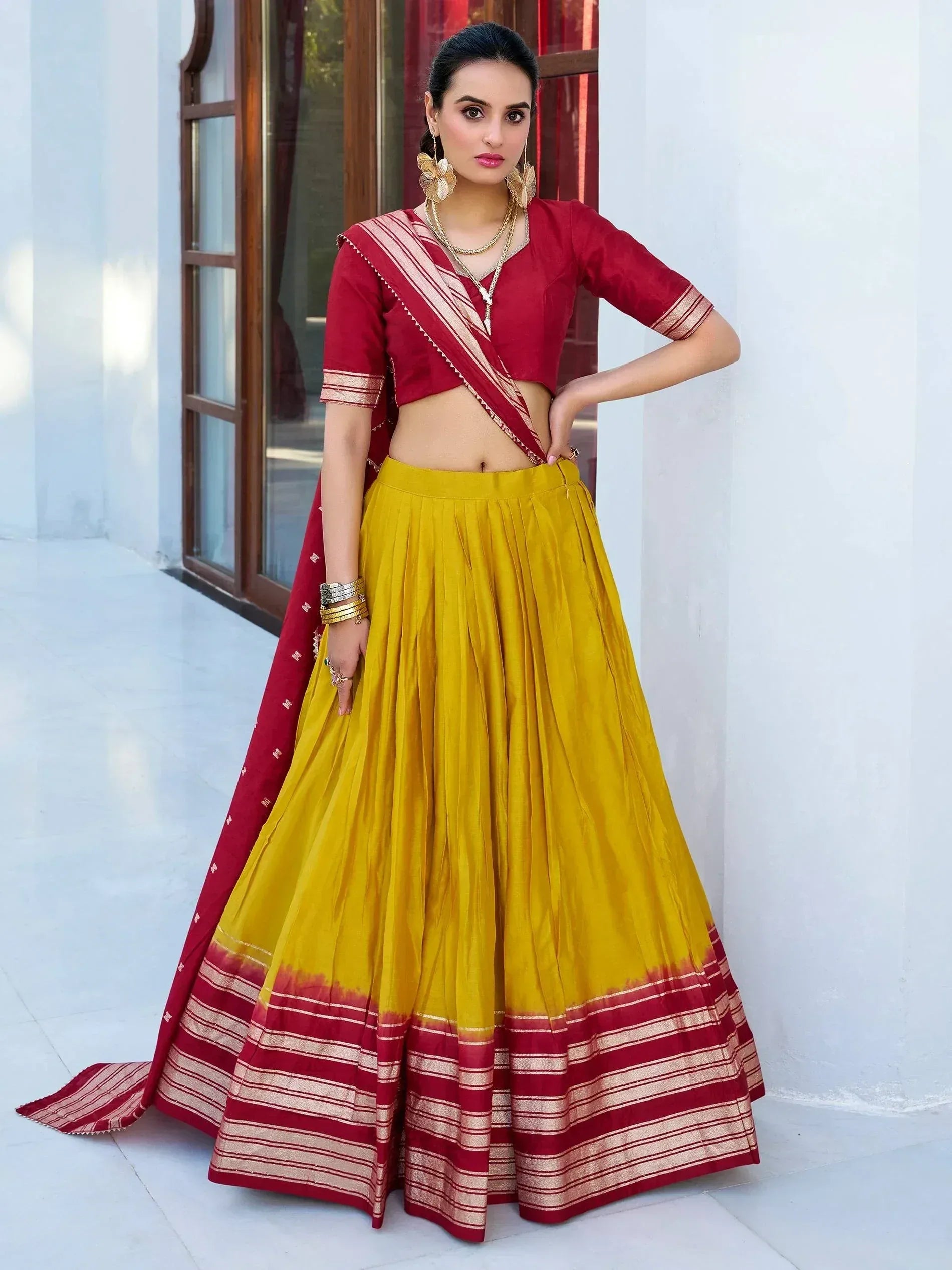Red and yellow designer lehenga choli with pleated skirt and striped border, perfect for Indian ethnic wear