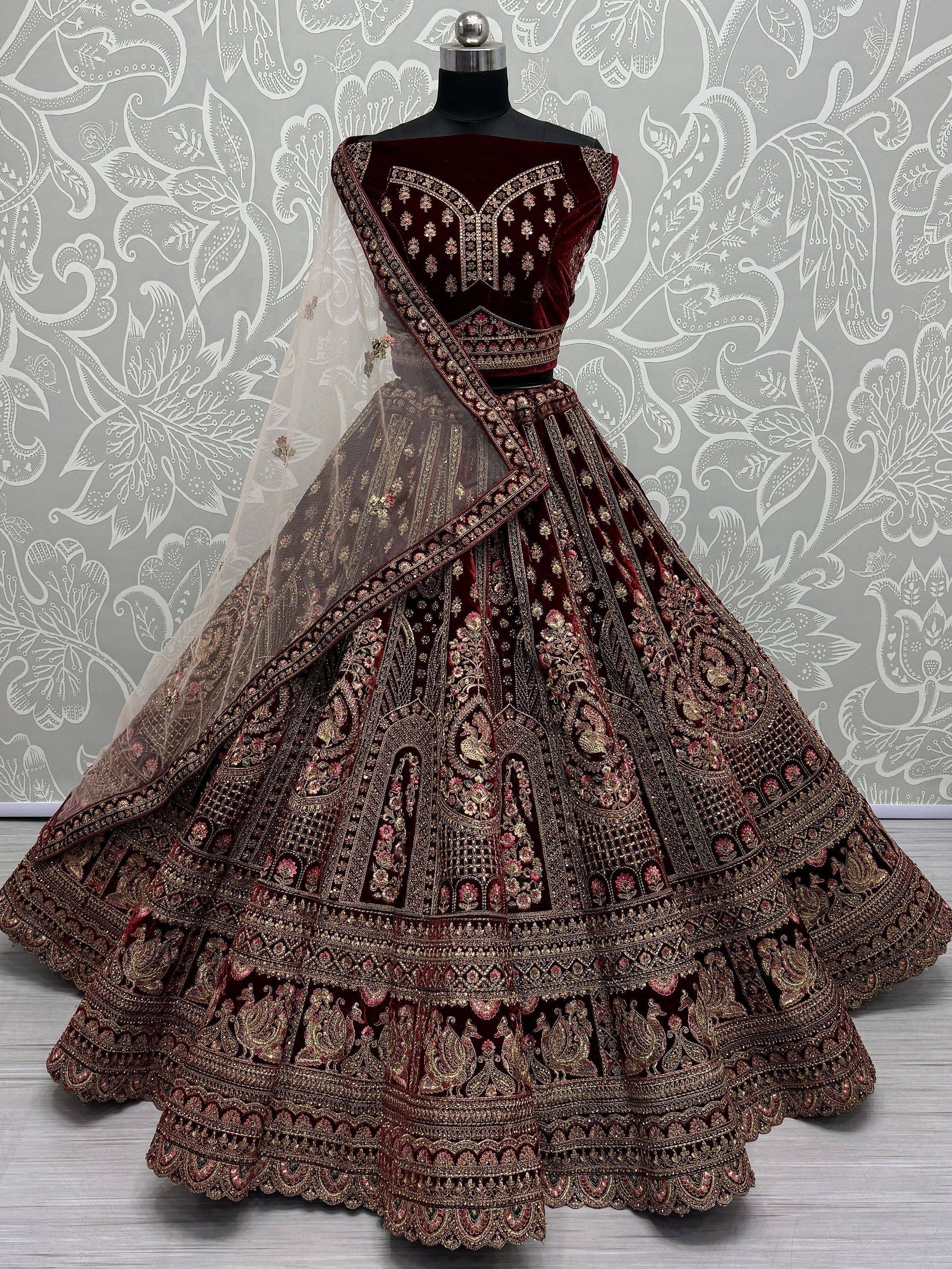 Burgundy velvet designer lehenga choli with heavy gold embroidery and sheer dupatta, perfect for Indian weddings