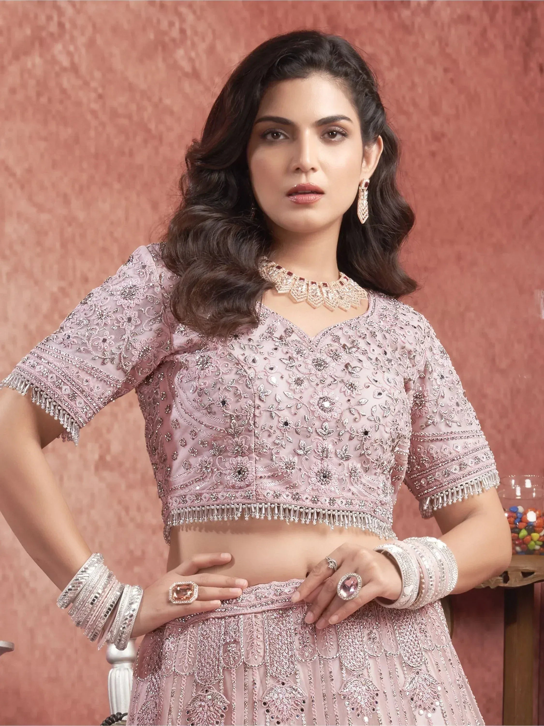 Pink embroidered lehenga choli with heavy embellishments and matching jewelry for Indian ethnic wear
