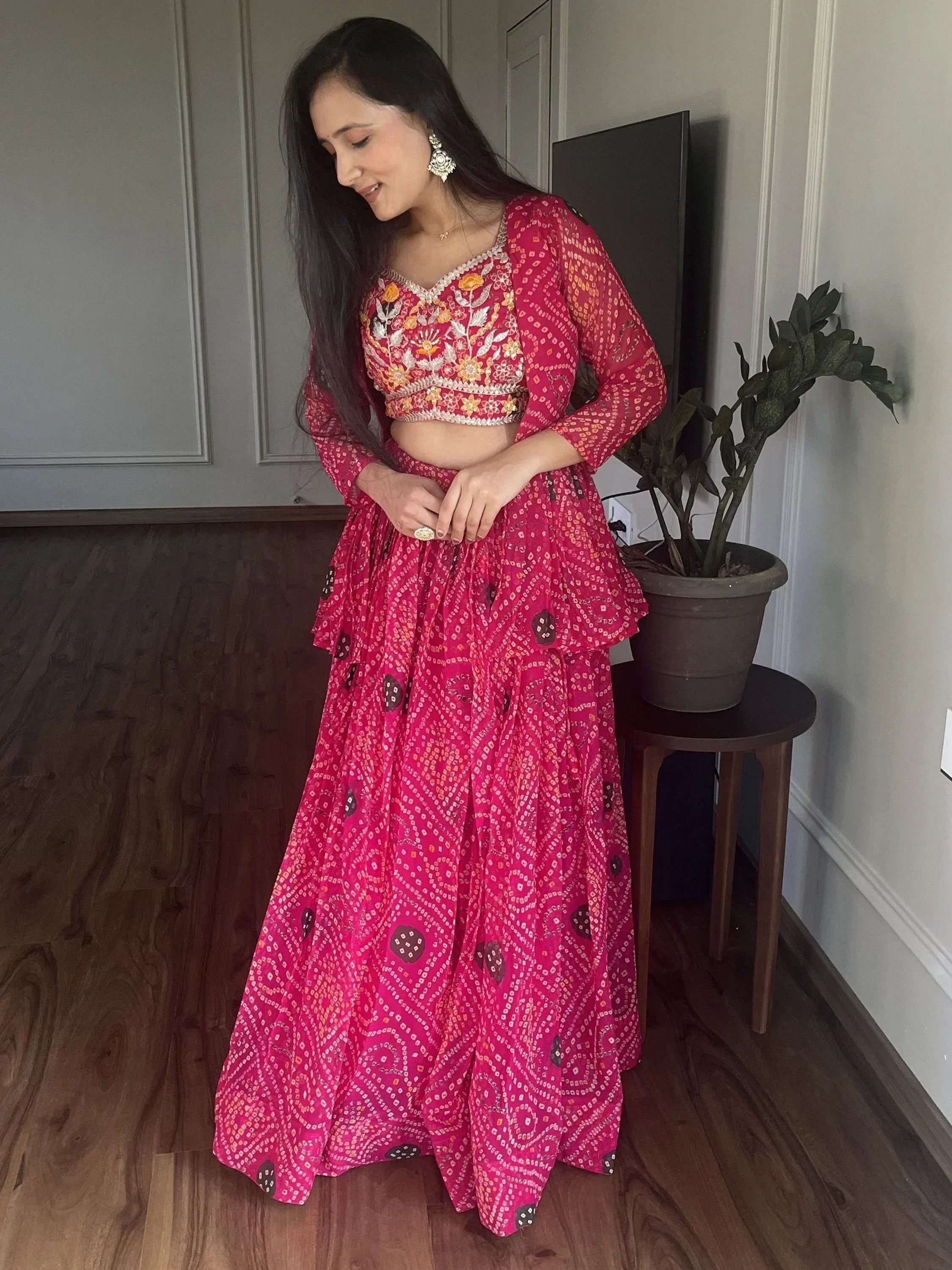 Woman in vibrant pink embroidered lehenga choli with floral motifs, perfect for Indian ethnic wear occasions