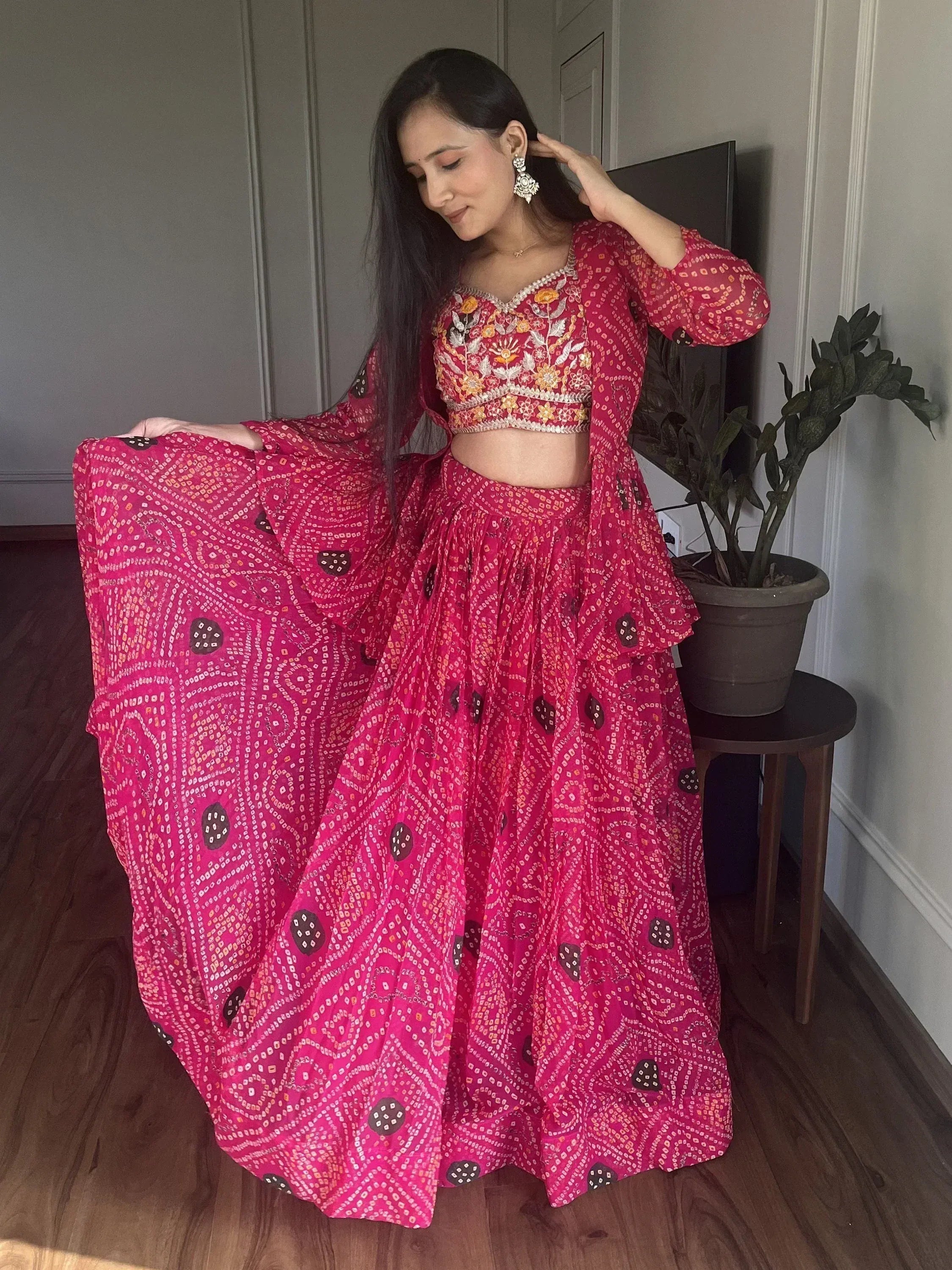Woman in vibrant pink embroidered lehenga choli with floral motifs, showcasing Indian ethnic wear.