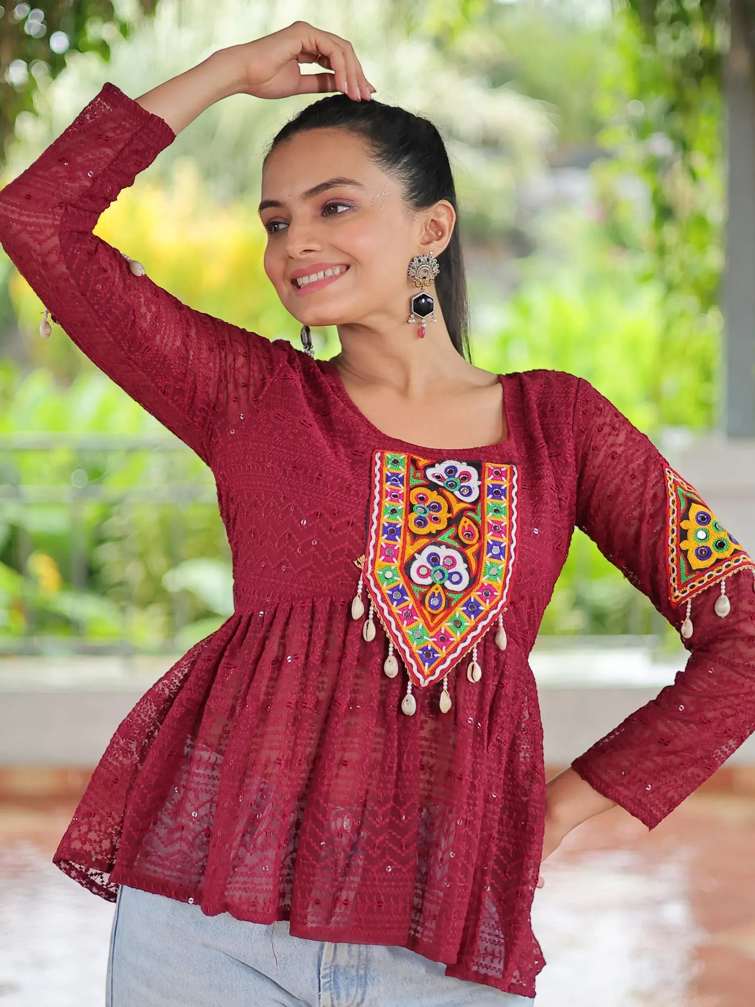 Maroon ethnic lace top with colorful mirror embroidery and tassels, paired with jeans for casual wear